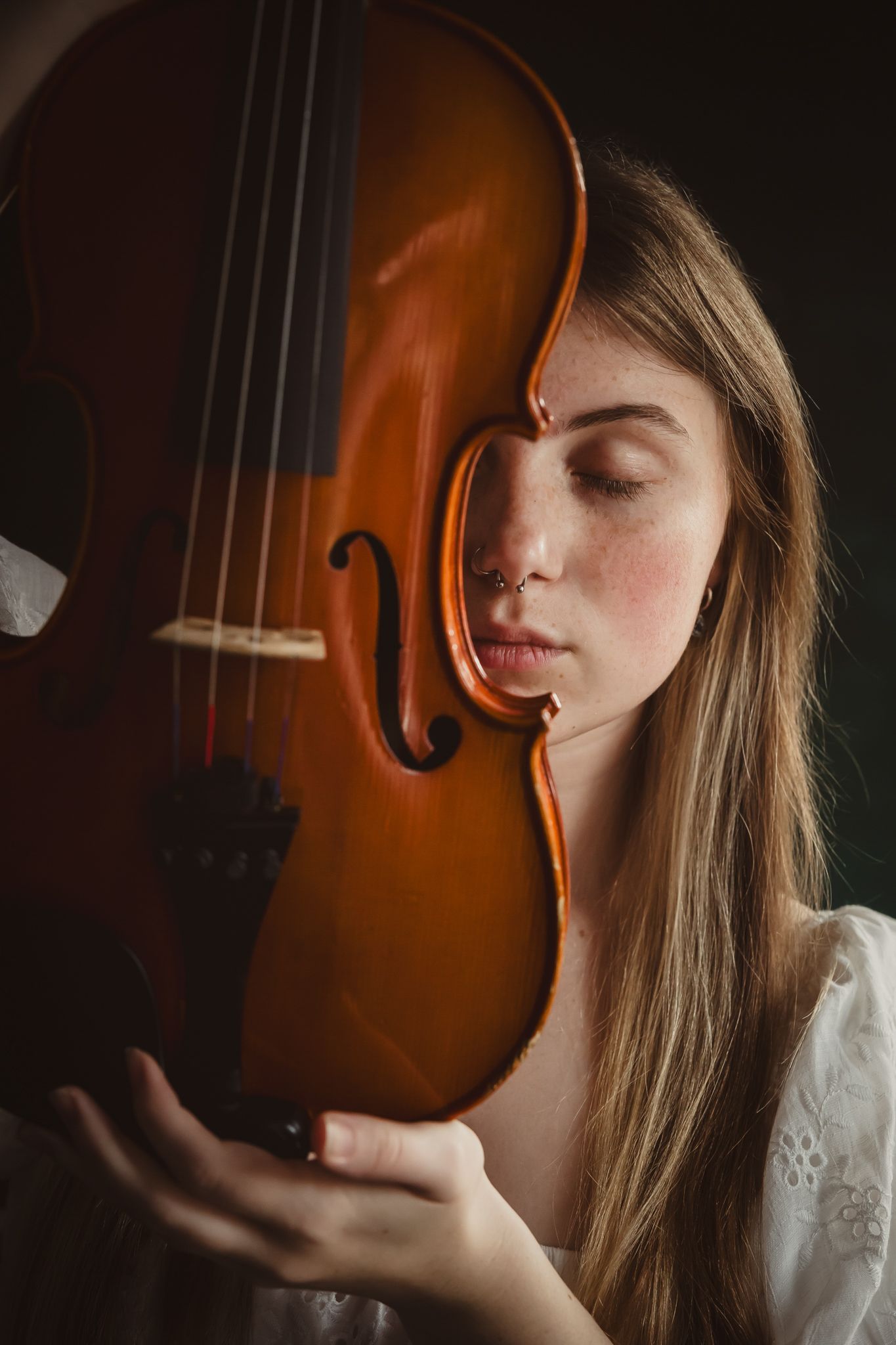 A series of artistic portraits showing a violin and a person in soft lighting against a dark background.