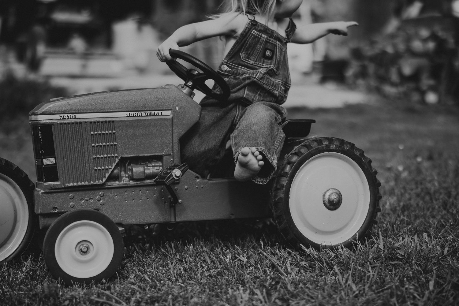 Vintage toy tractors lined up on grass in black and white photography.