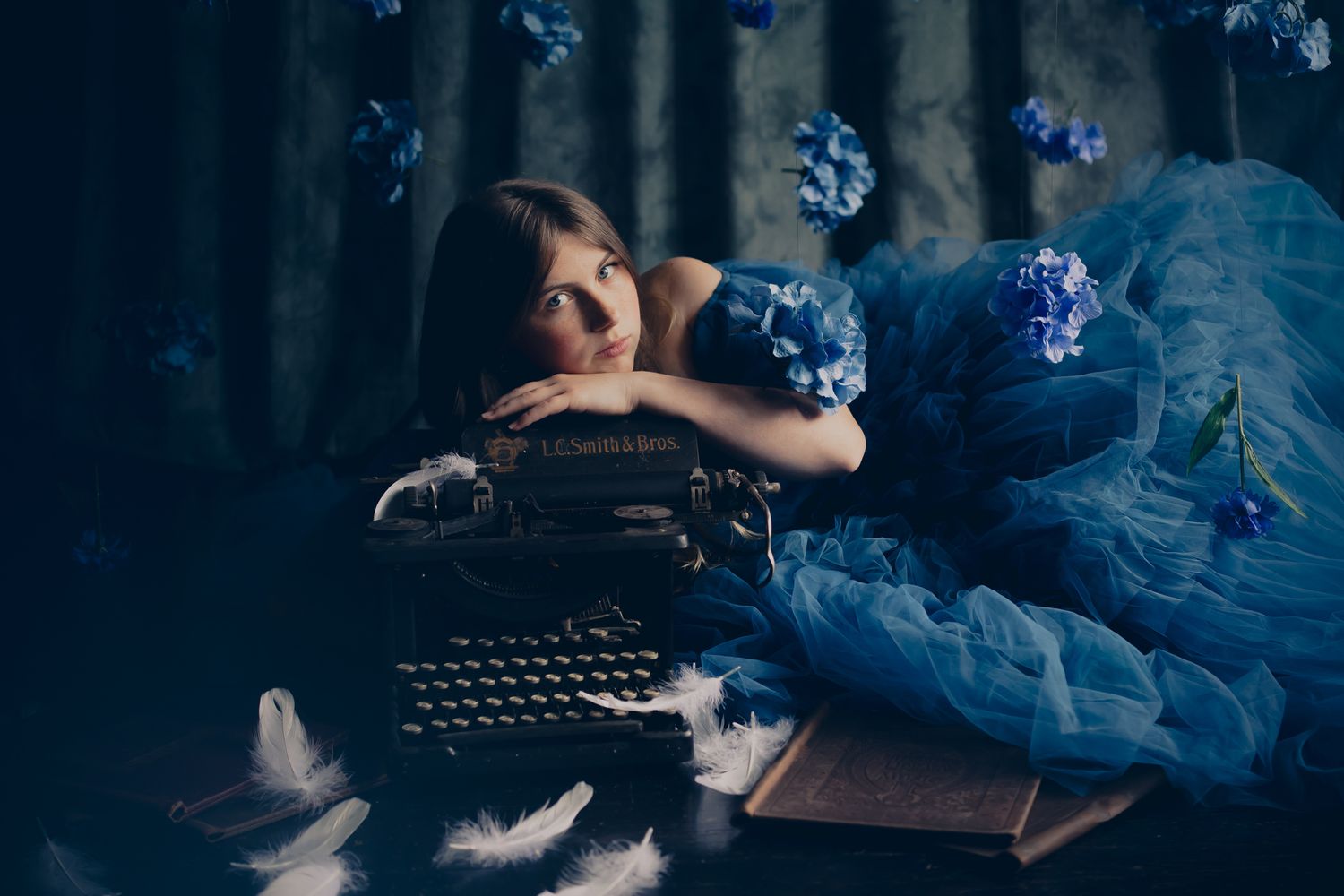 A series of dark moody photos featuring vintage typewriters and floating feathers with ethereal blue lighting effects.