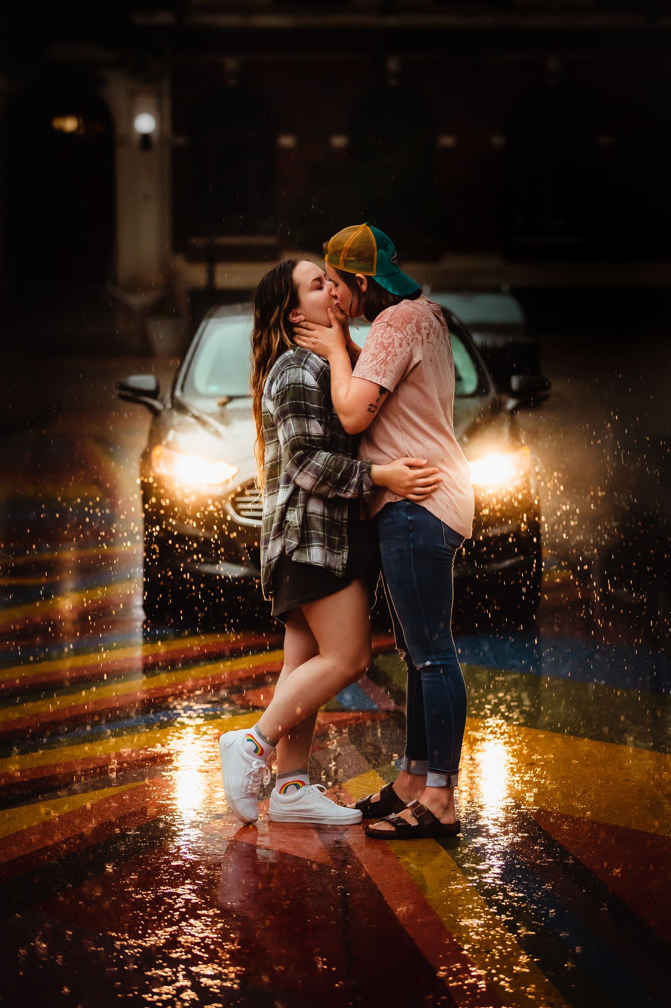 A couple embraces in the rain at night with sparkling lights creating a romantic atmosphere.
