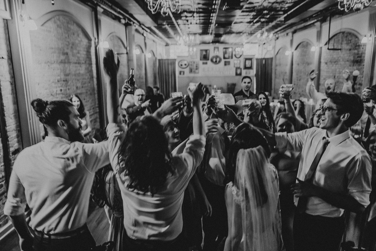 Large group of guests dancing together at a lively wedding reception on a dance floor.