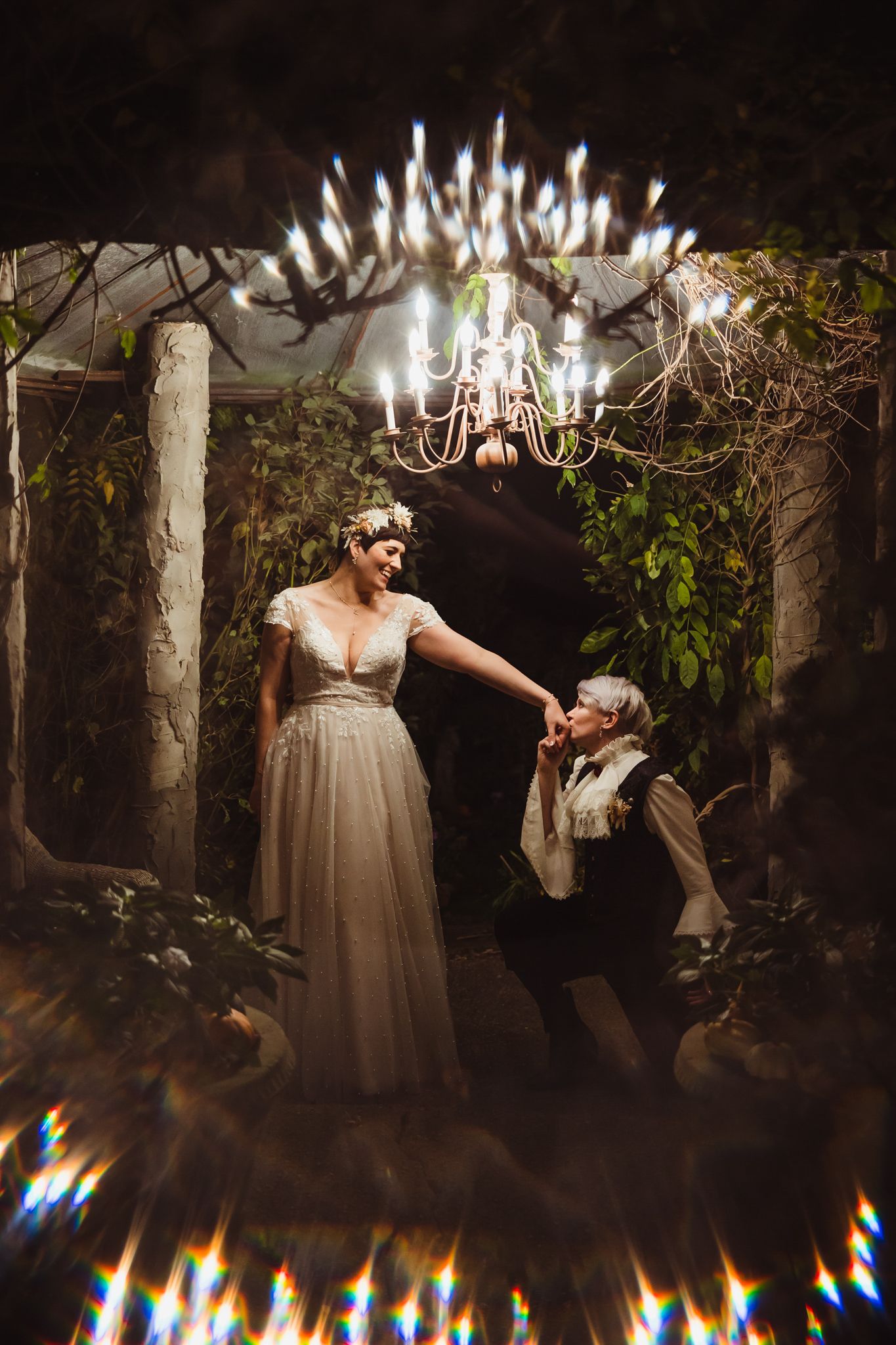 Romantic dance scene under a vintage chandelier in a dimly lit garden setting with magical lighting effects.