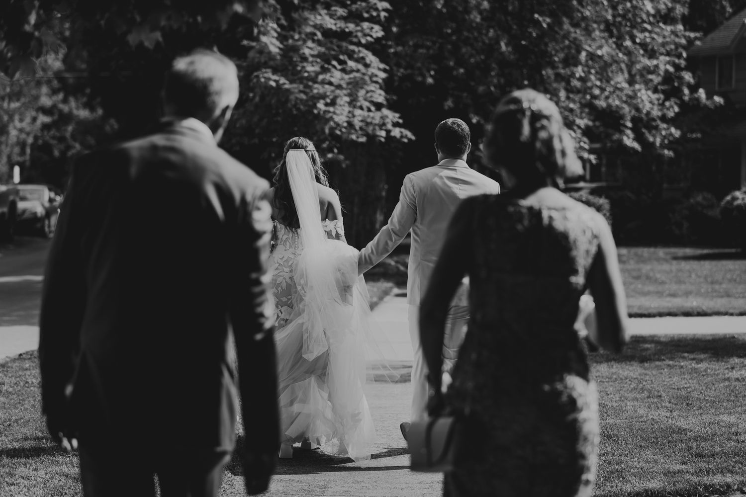 Black and white film strip showing guests walking outdoors at a wedding ceremony.