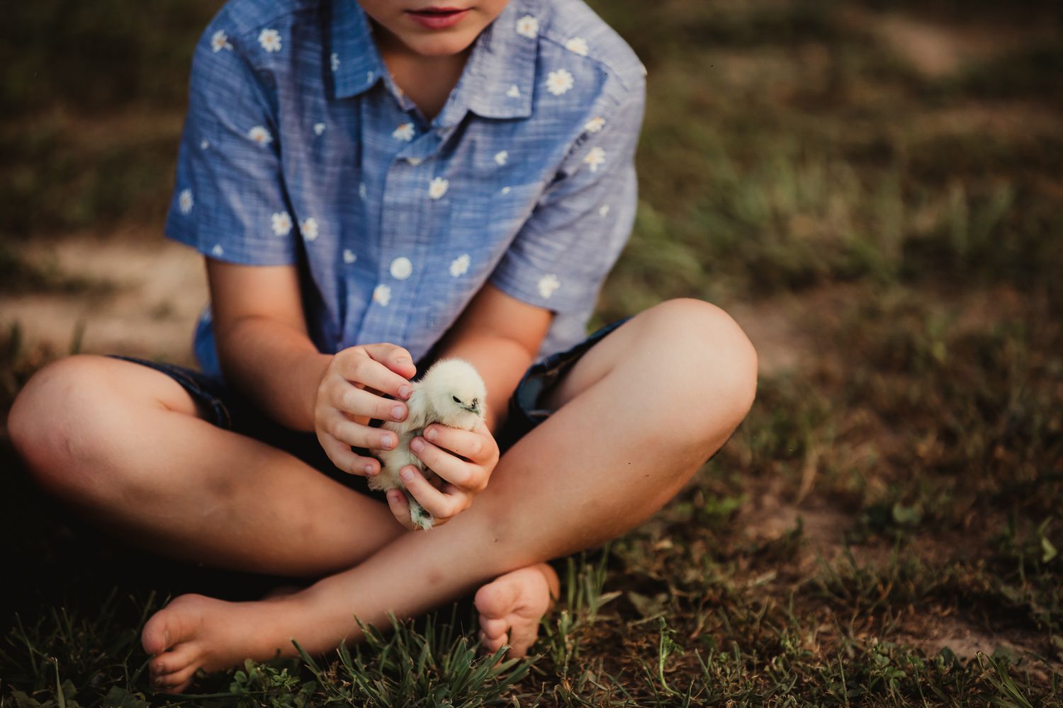 Casual outdoor sitting pose on grass with denim clothing.