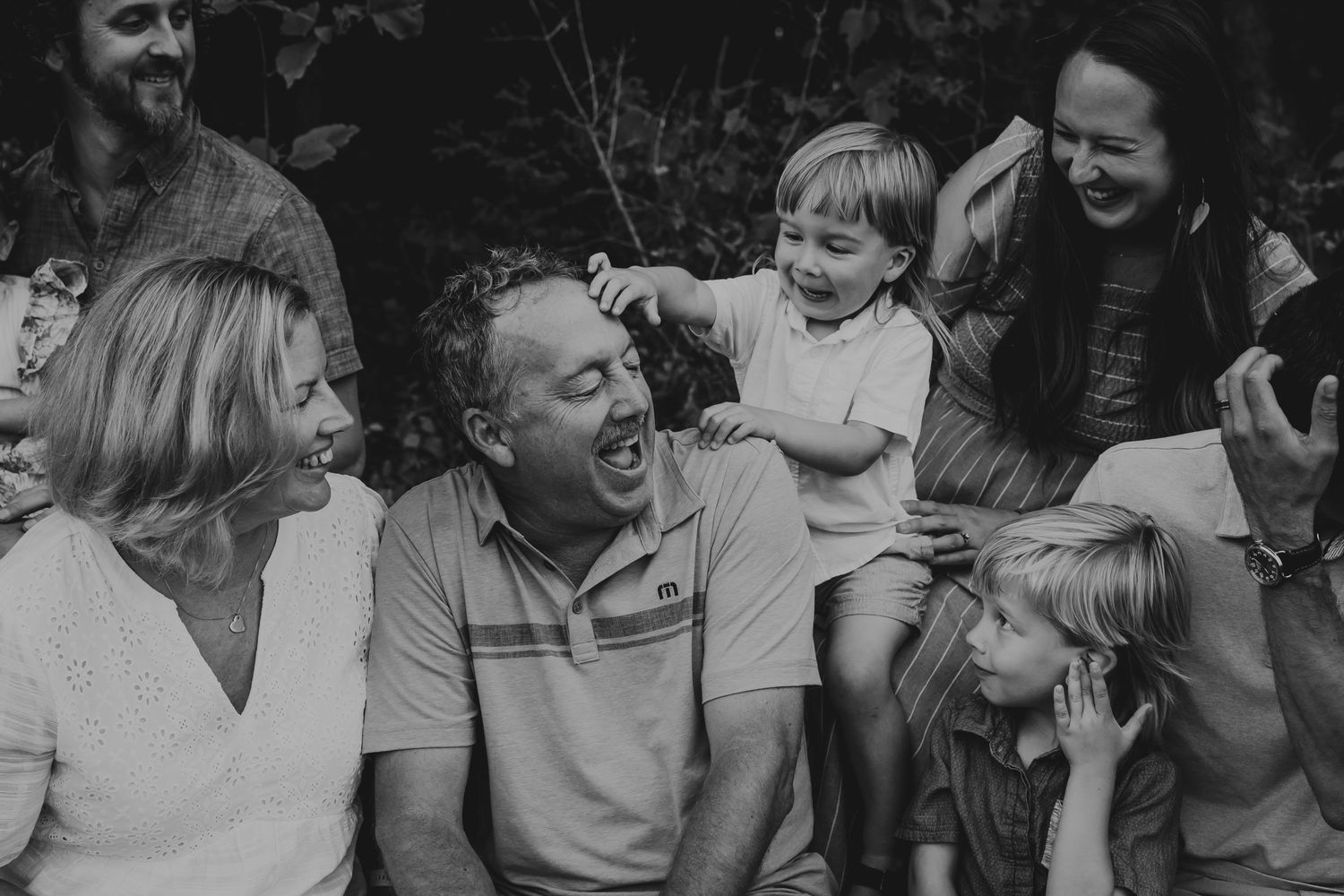 Black and white photo of a happy family gathering outdoors sharing a joyful moment together.