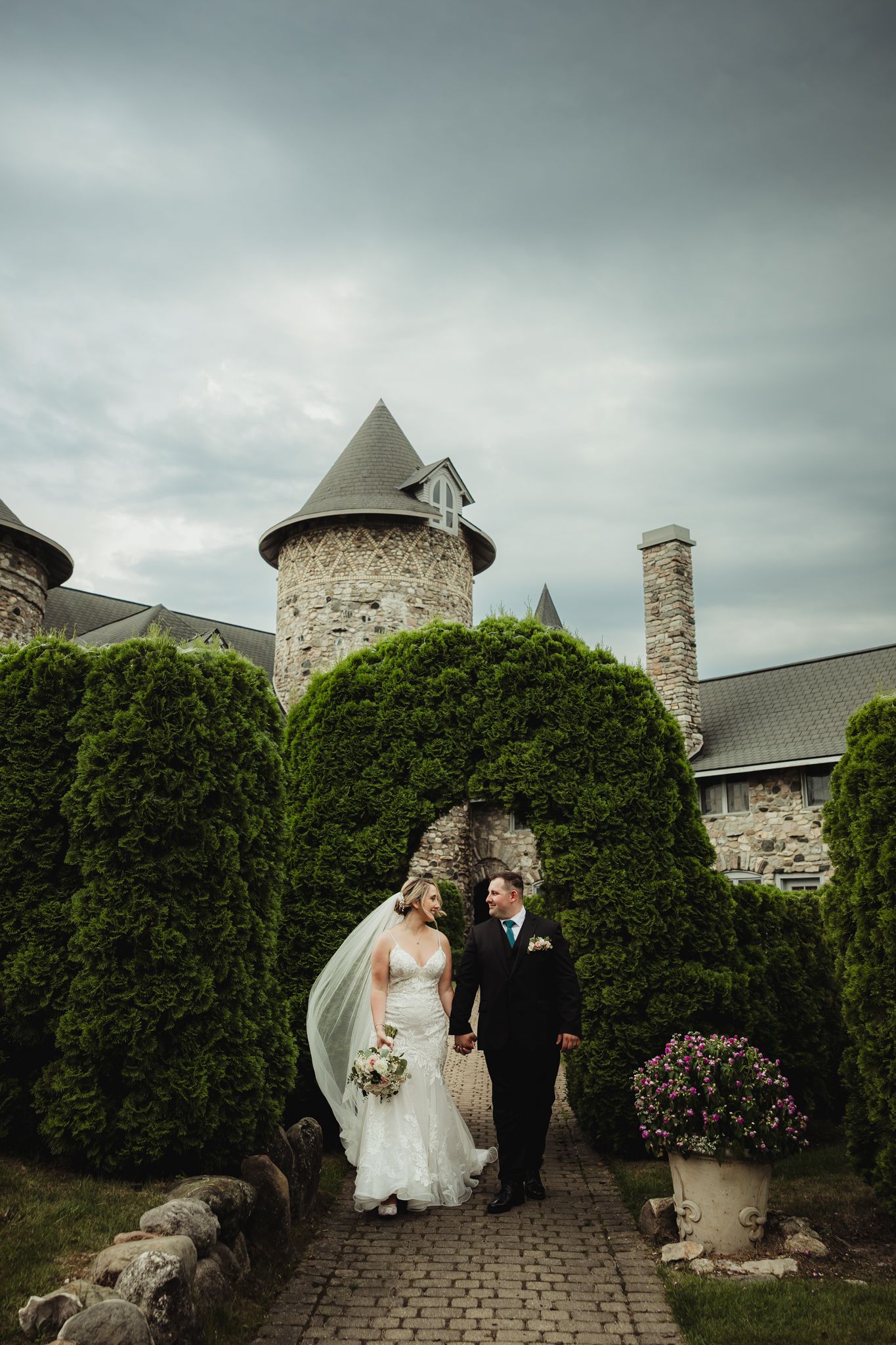 Classic castle wedding venue with stone towers and manicured hedges under moody skies.