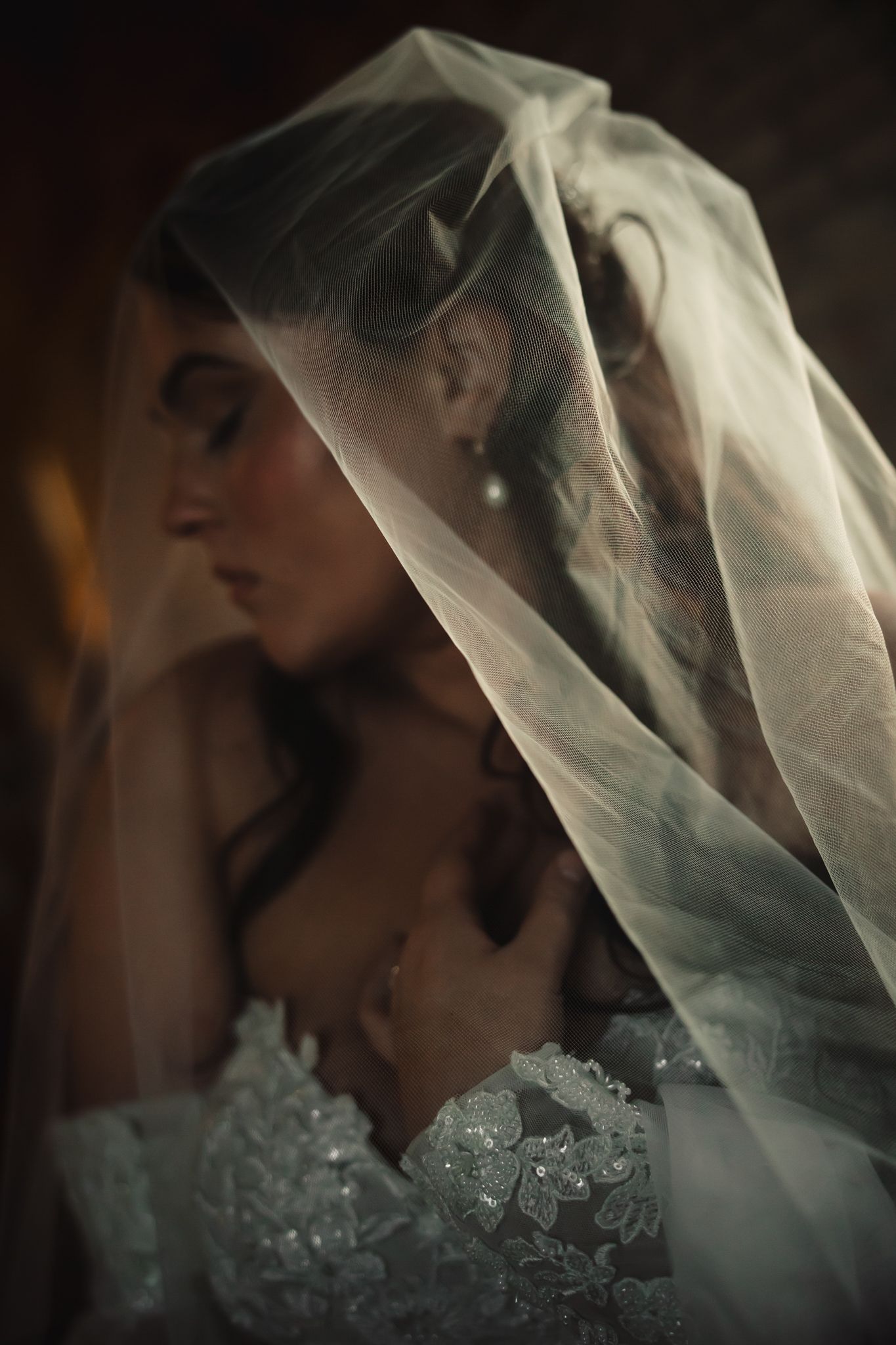 Close-up detail of delicate lace wedding veil against dark background.