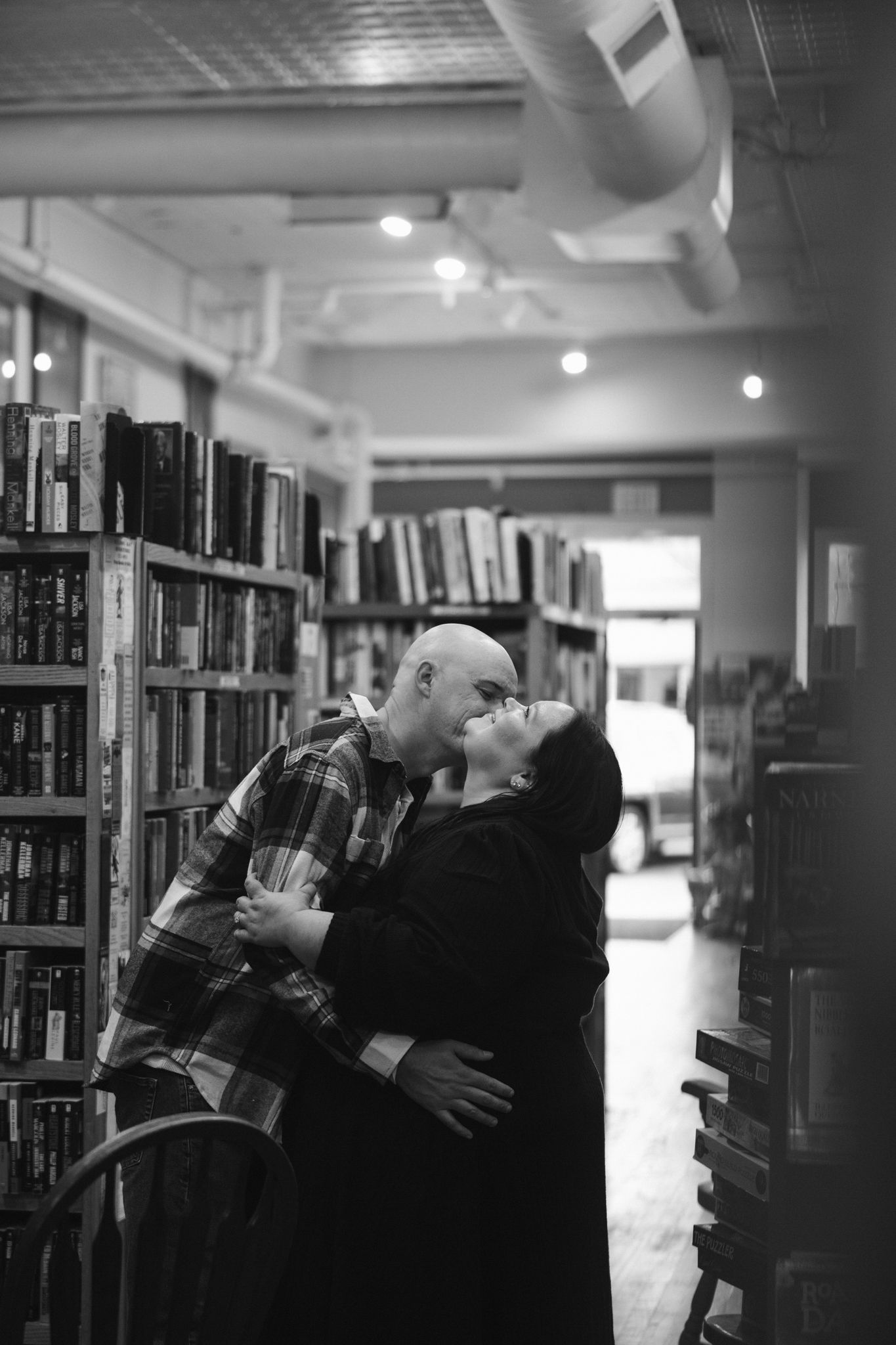 Black and white library engagement photos between bookshelves.