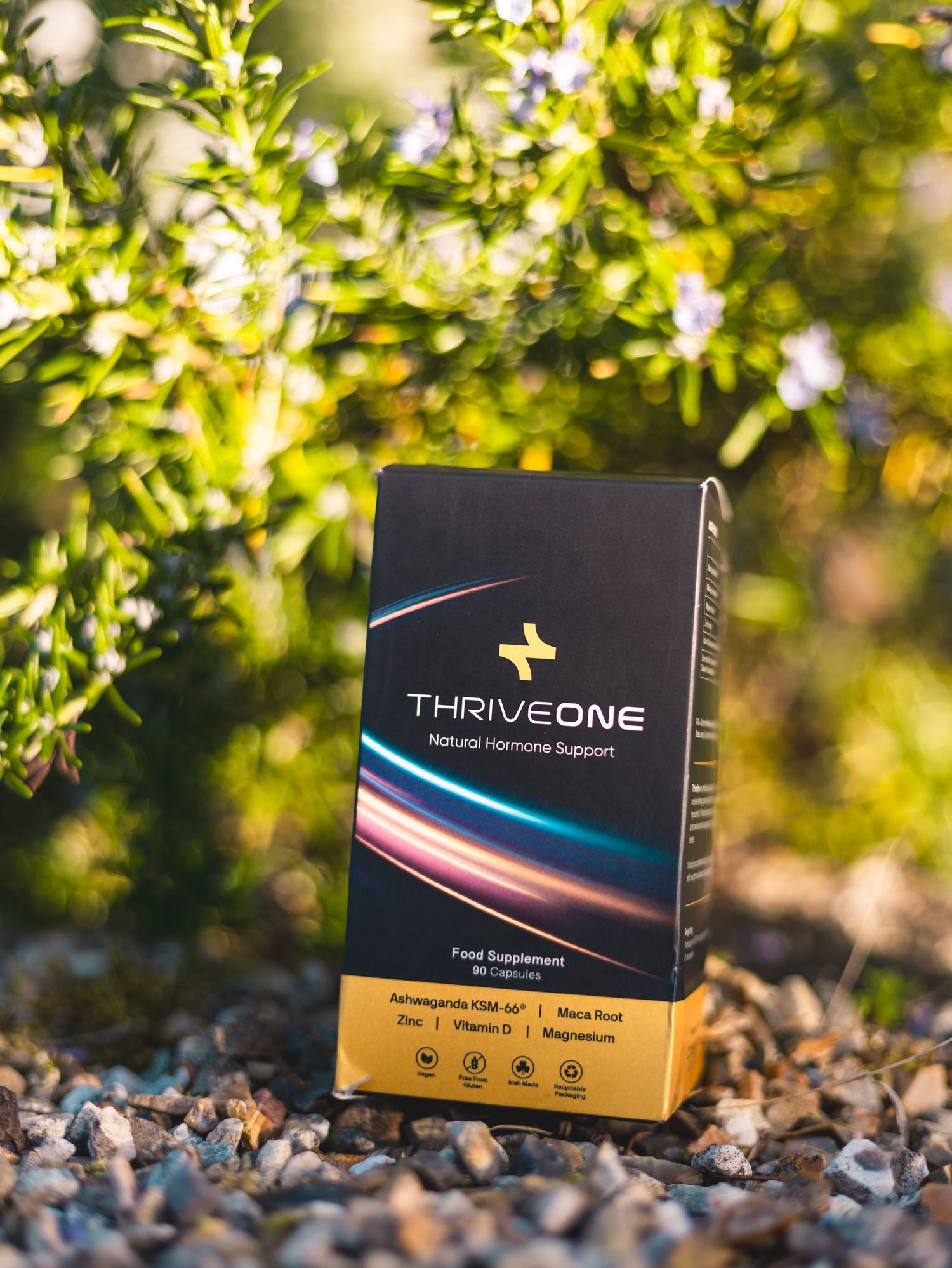 Product packaging boxes displayed on rocky ground with sunlit foliage in background.