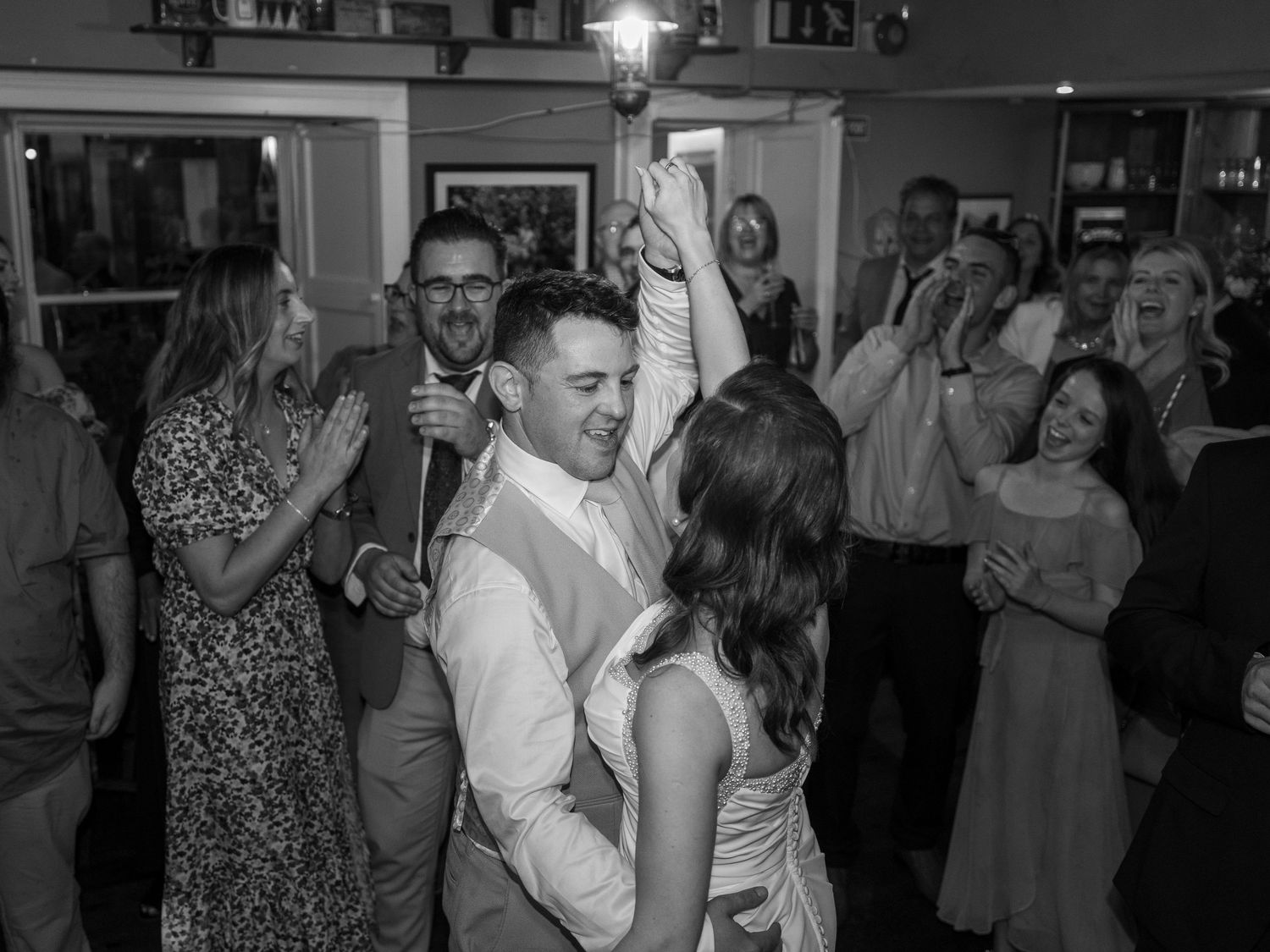 Wedding guests dancing and celebrating at an indoor reception venue.
