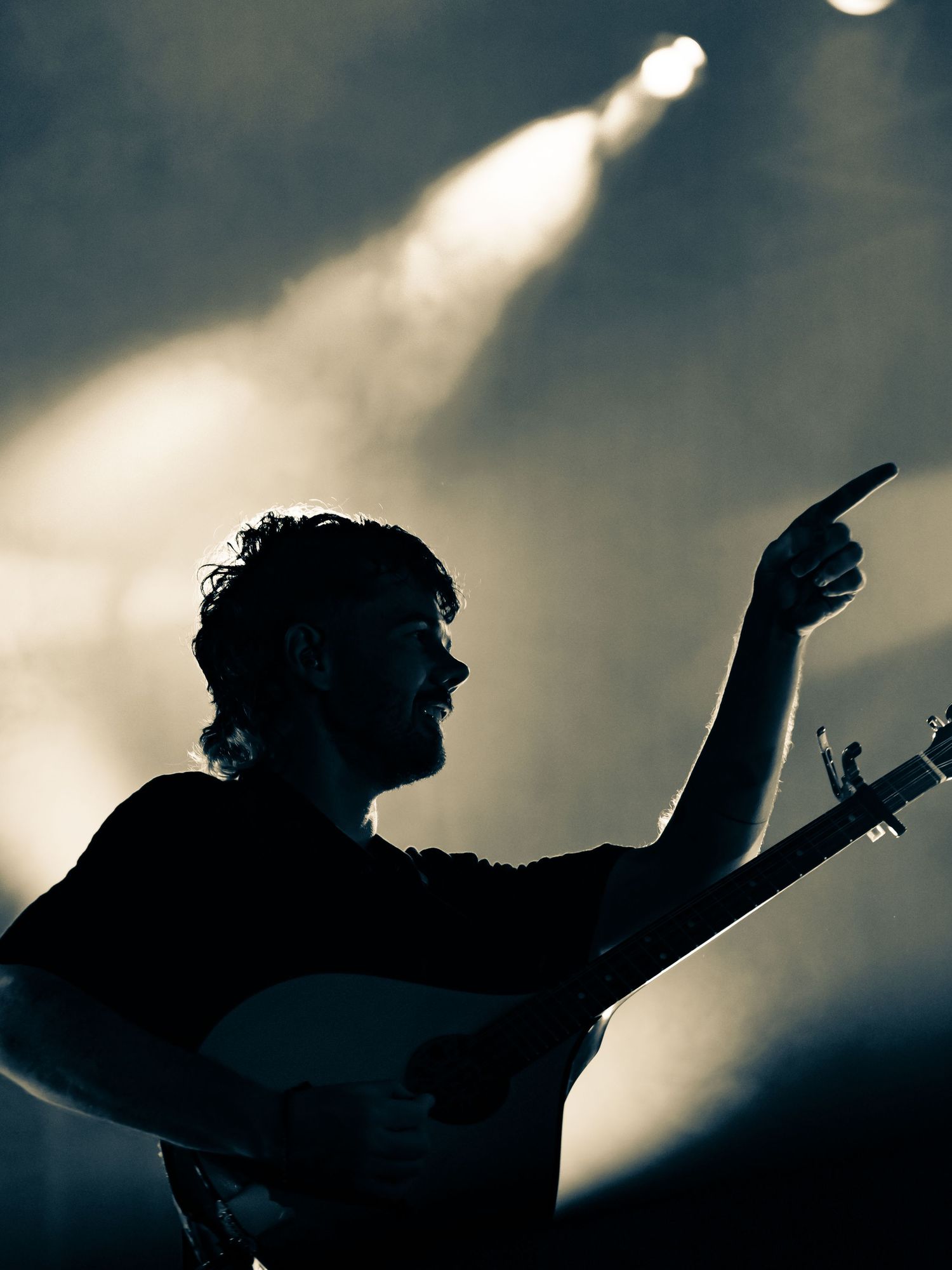 Dramatic silhouettes of performers against a moody sky with bright stage lighting creating an atmospheric effect.