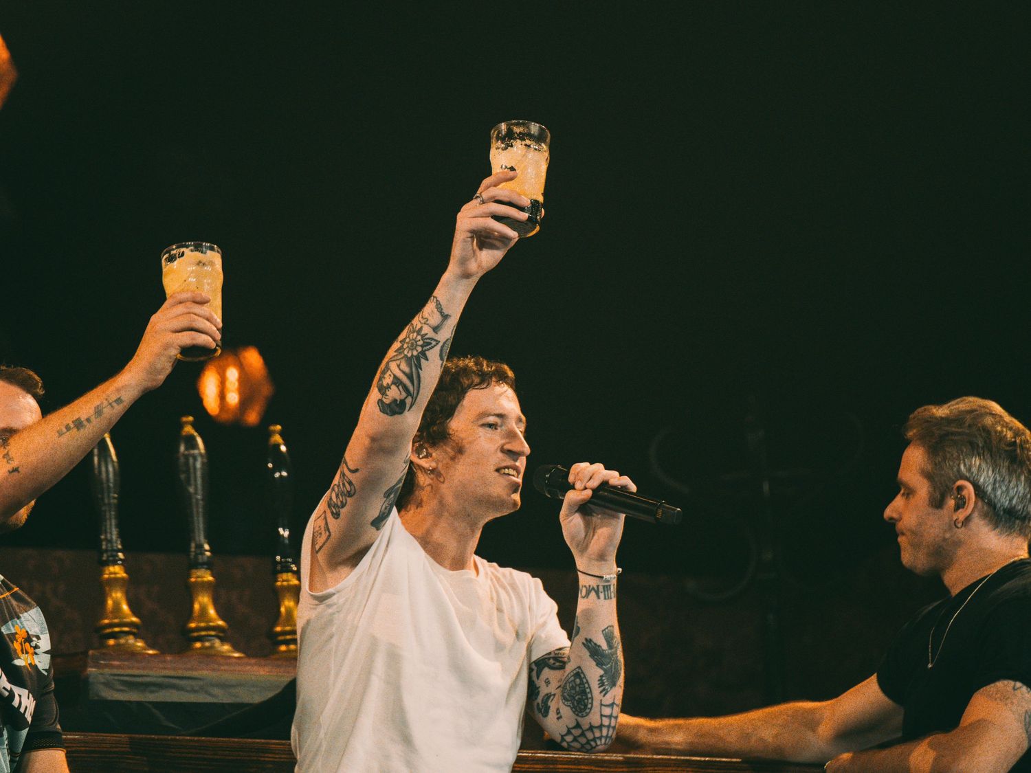People raising drinks in celebration at a dimly lit venue.