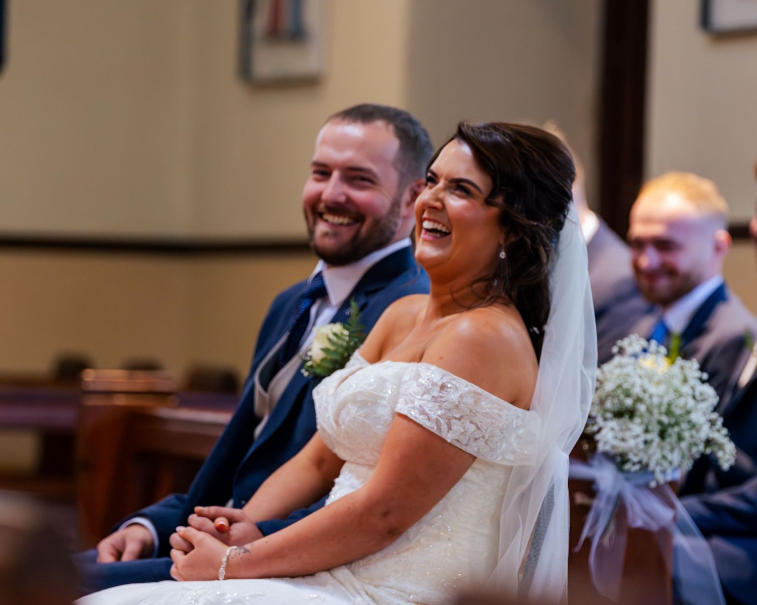 Happy couple and wedding party celebrate inside church with joyful laughter.