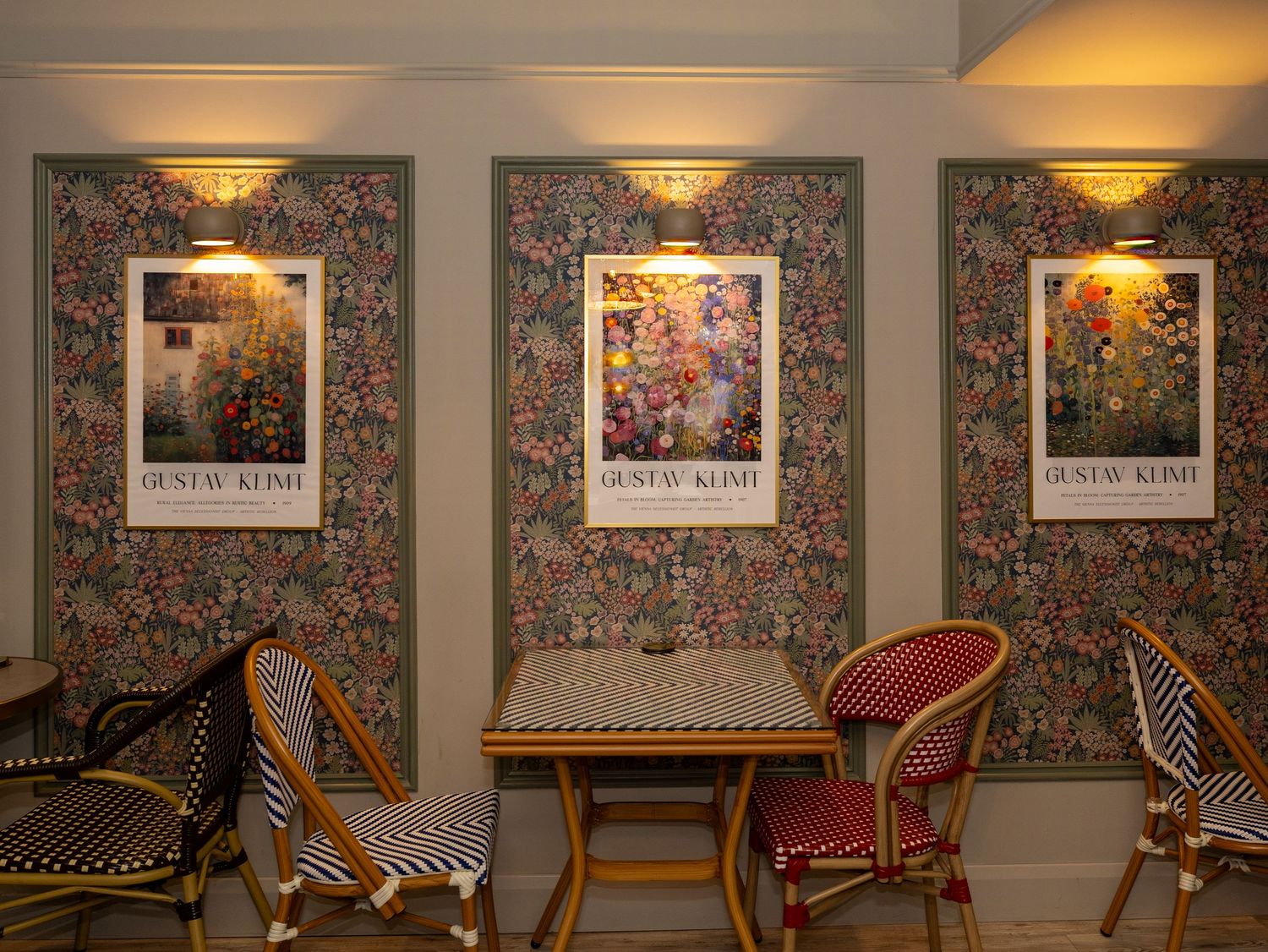 Elegant restaurant interior with floral wallpaper, ornate sconces, and red velvet chairs along a curved wall.