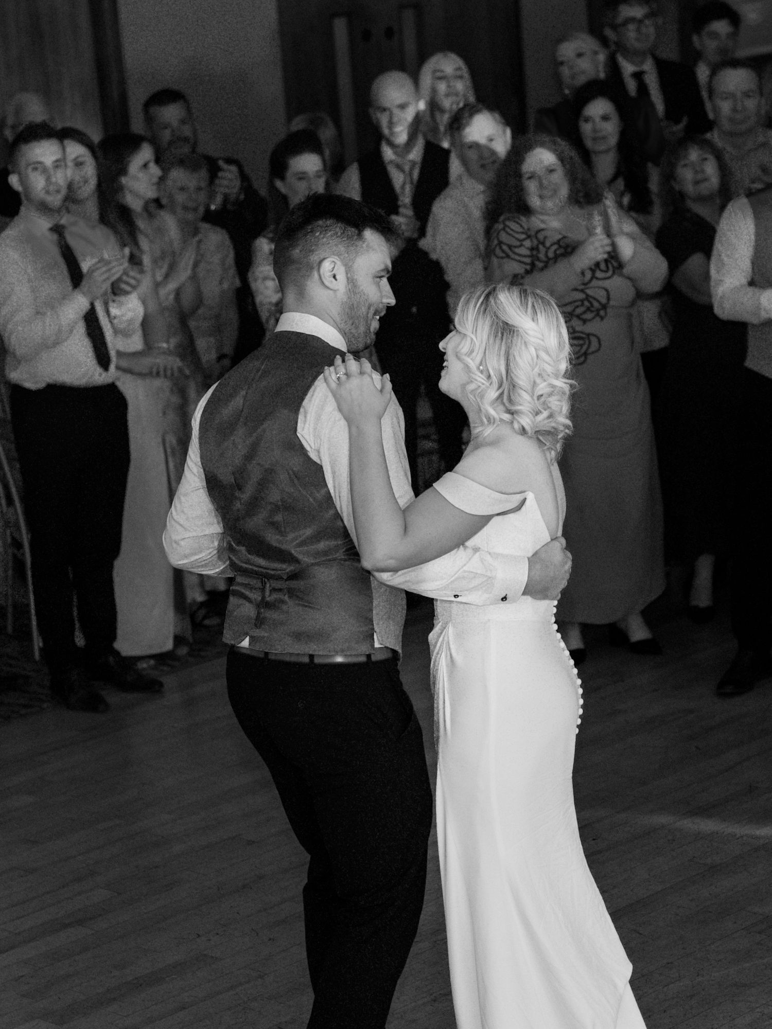 A black and white photo series of a couple dancing at their wedding reception with guests watching in the background.