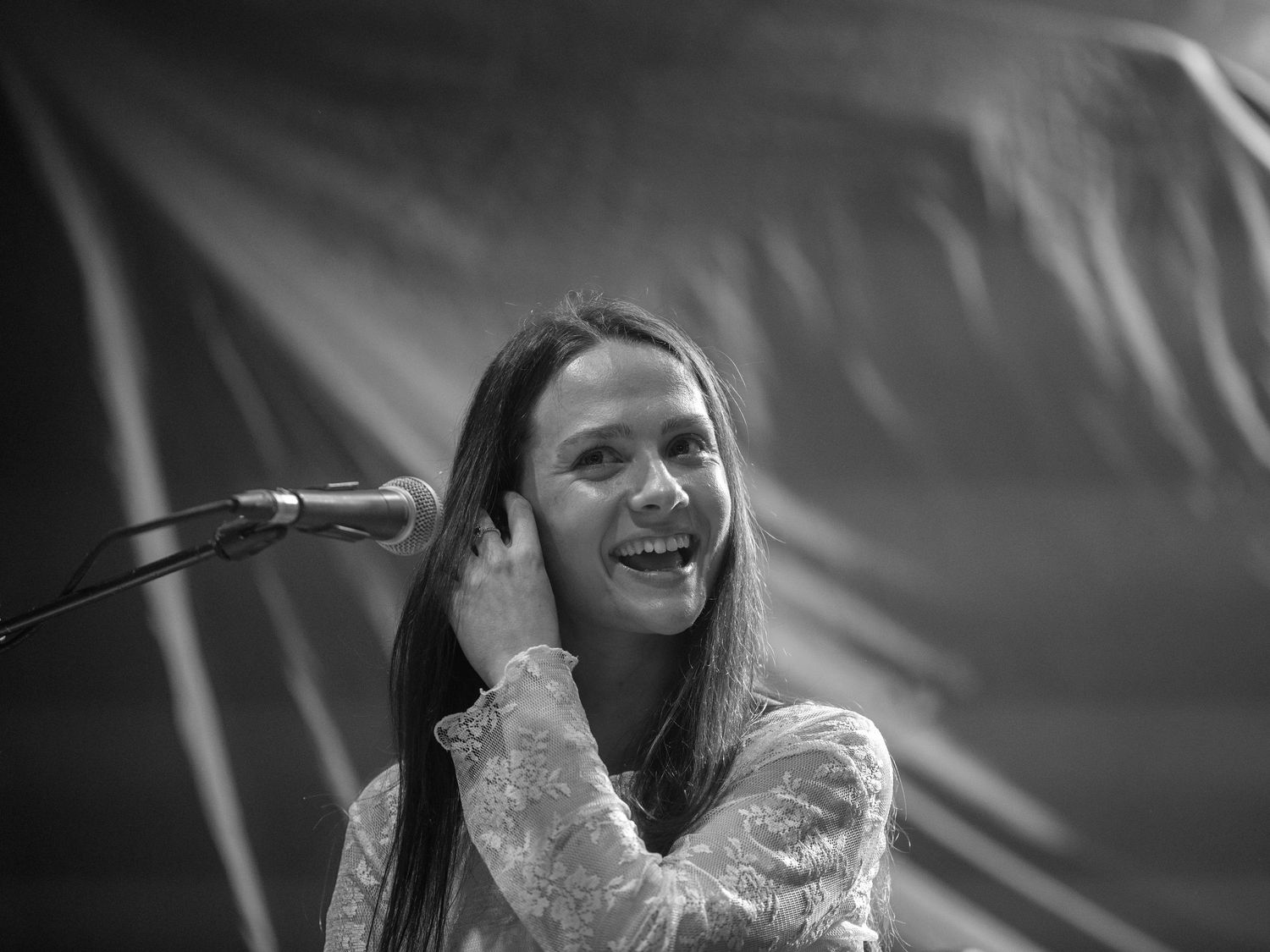 A performer smiles while adjusting headphones during a musical performance on stage.