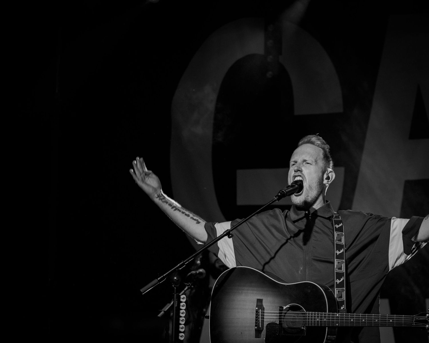 A series of black and white performance photos showing musicians singing and playing guitar on stage.