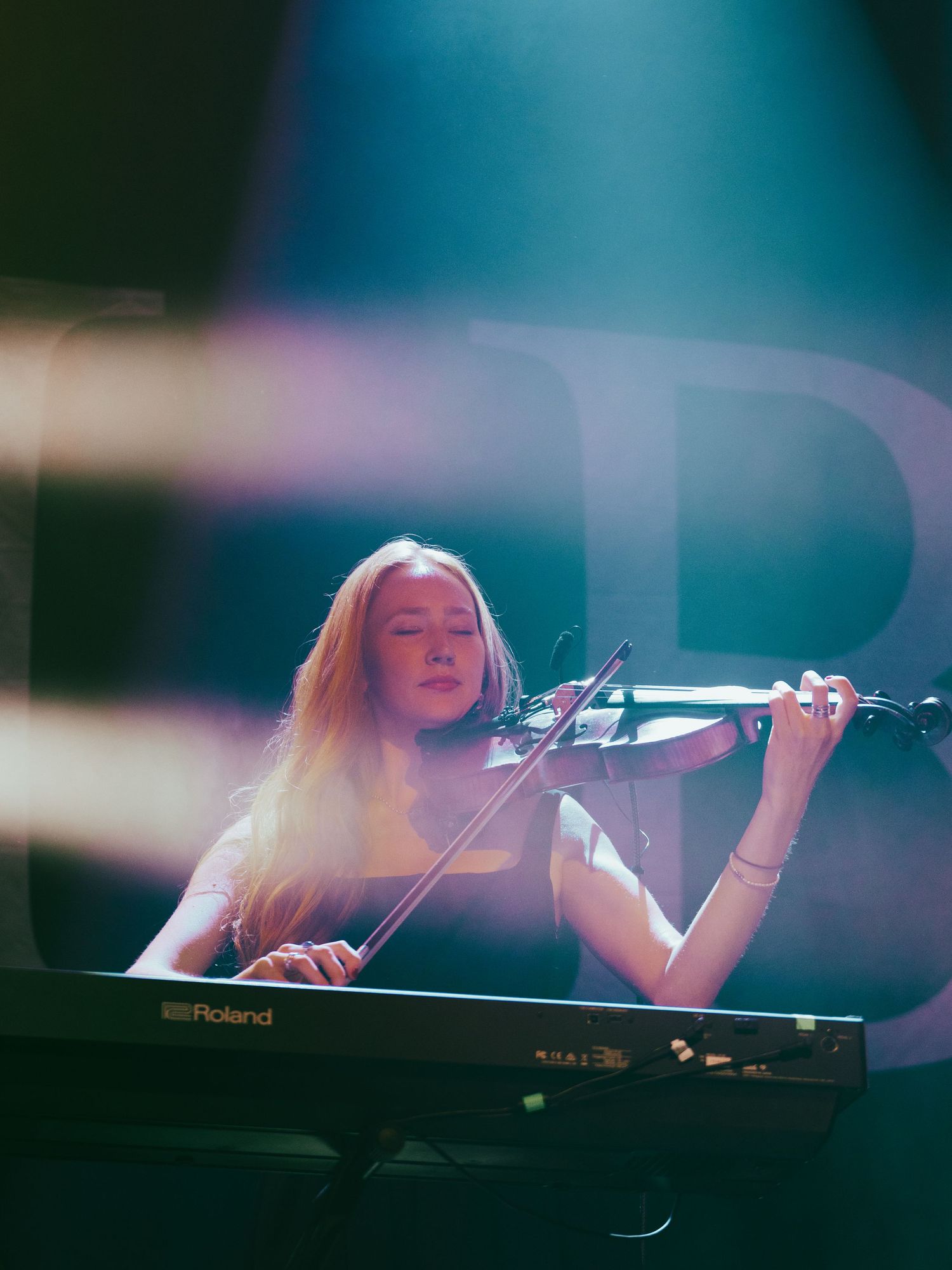 Musician performing on keyboard with atmospheric blue lighting and shallow depth of field.
