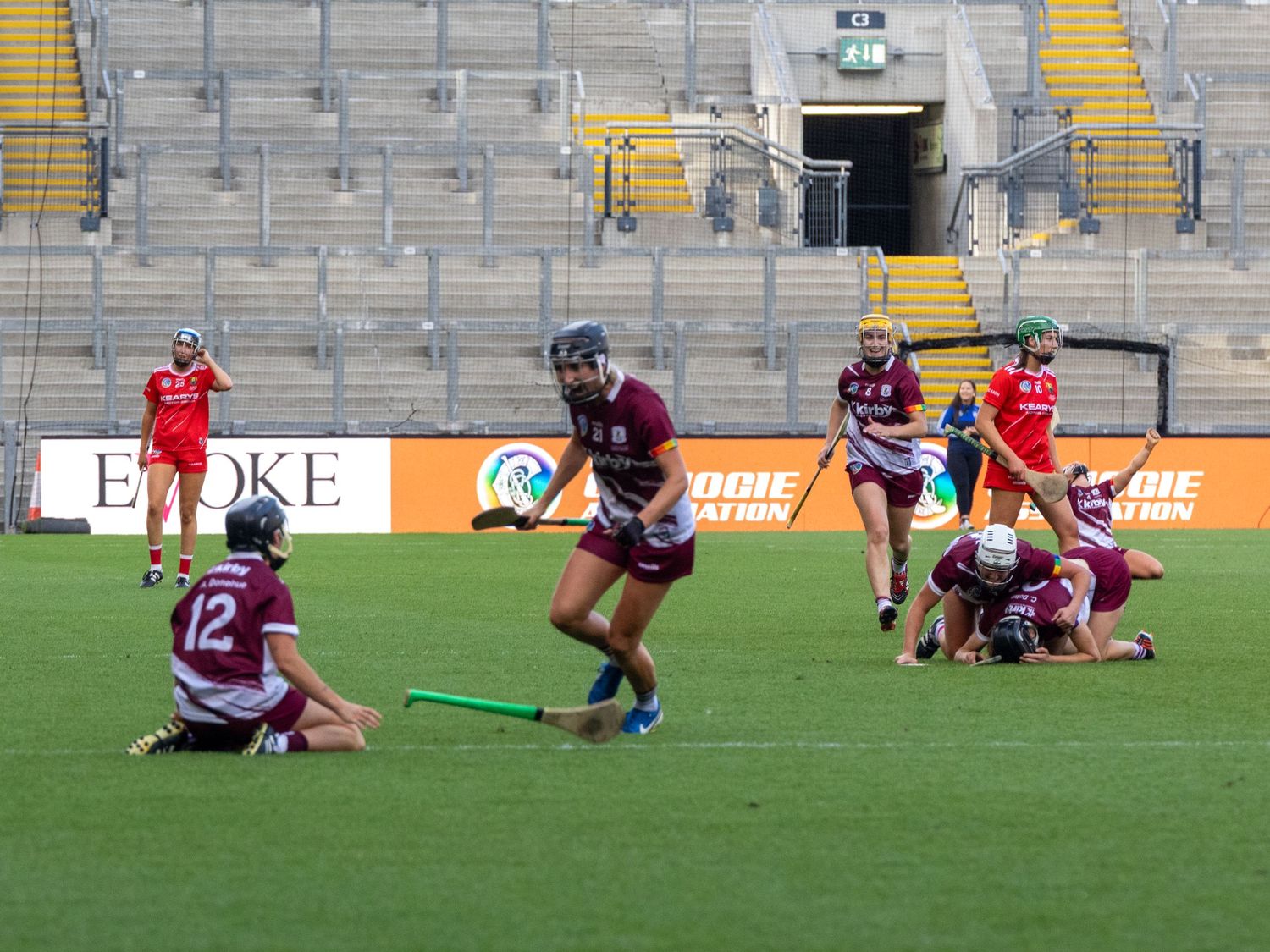 Rugby players scattered across an empty stadium field during a practice or training session.
