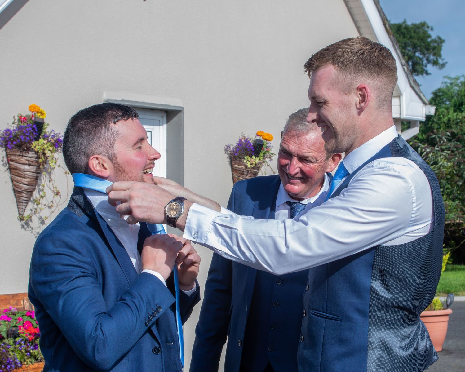 A sequence of photos showing two men in suits playfully interacting and laughing together outdoors.