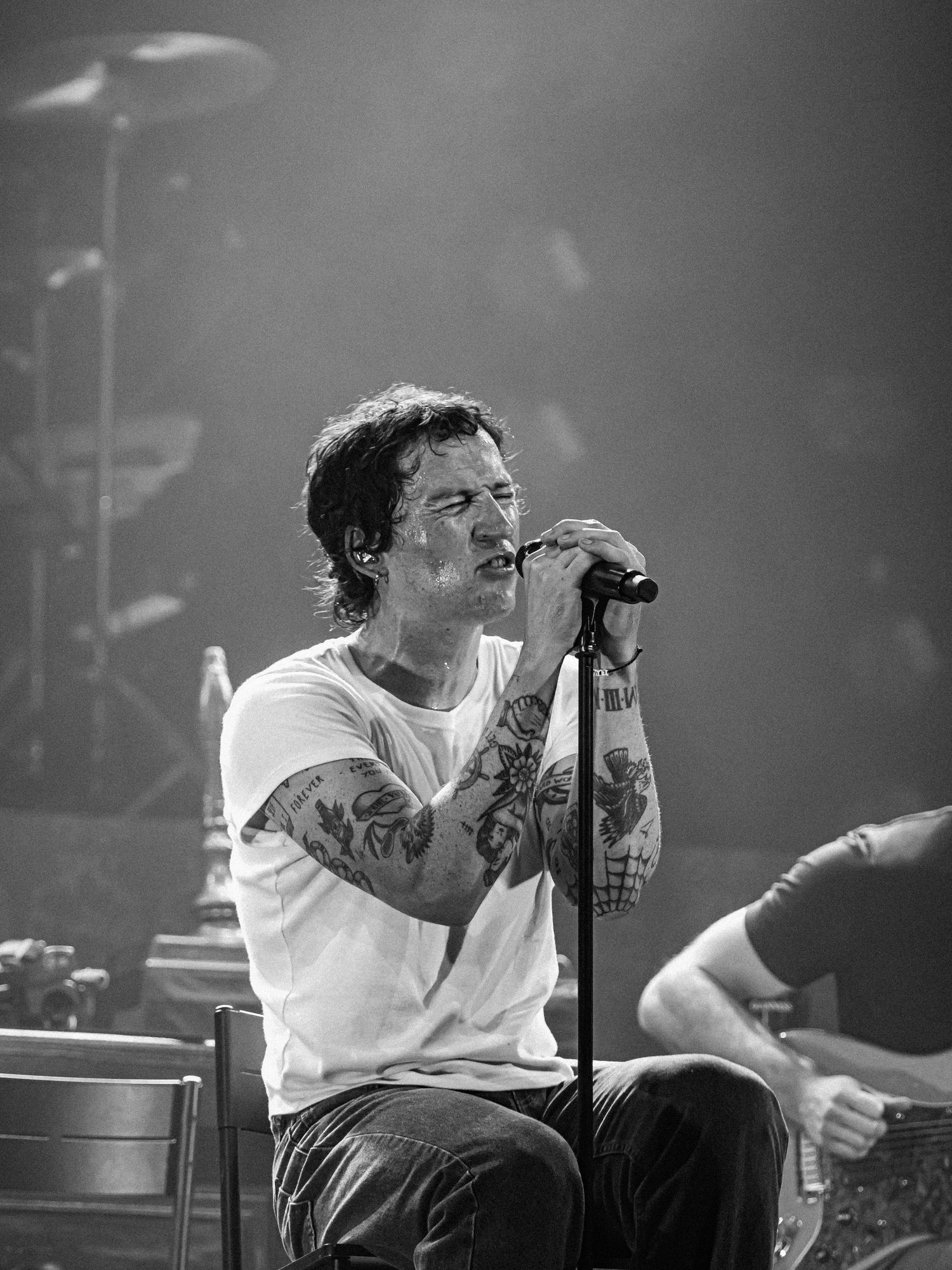 Black and white concert photography showing an energetic performance on stage with dramatic lighting.