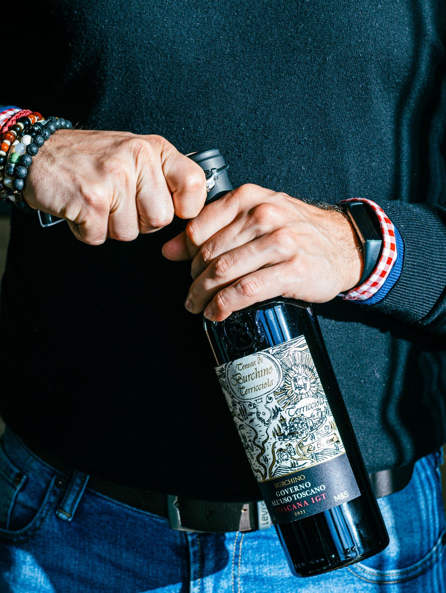 Hand holding a bottle of Don Papa rum against a dark background with dramatic lighting.