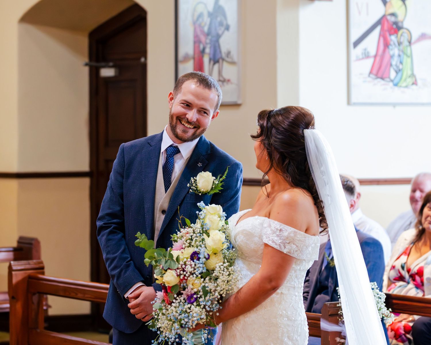 Wedding ceremony taking place in church with stained glass windows.