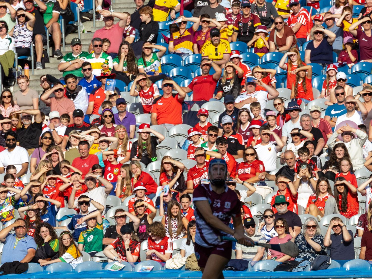 A packed stadium crowd wearing colorful jerseys and clothing fills the stands during a sporting event.