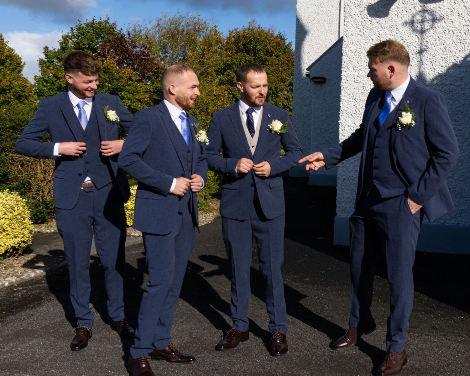 Groomsmen in navy suits posing casually outdoors.