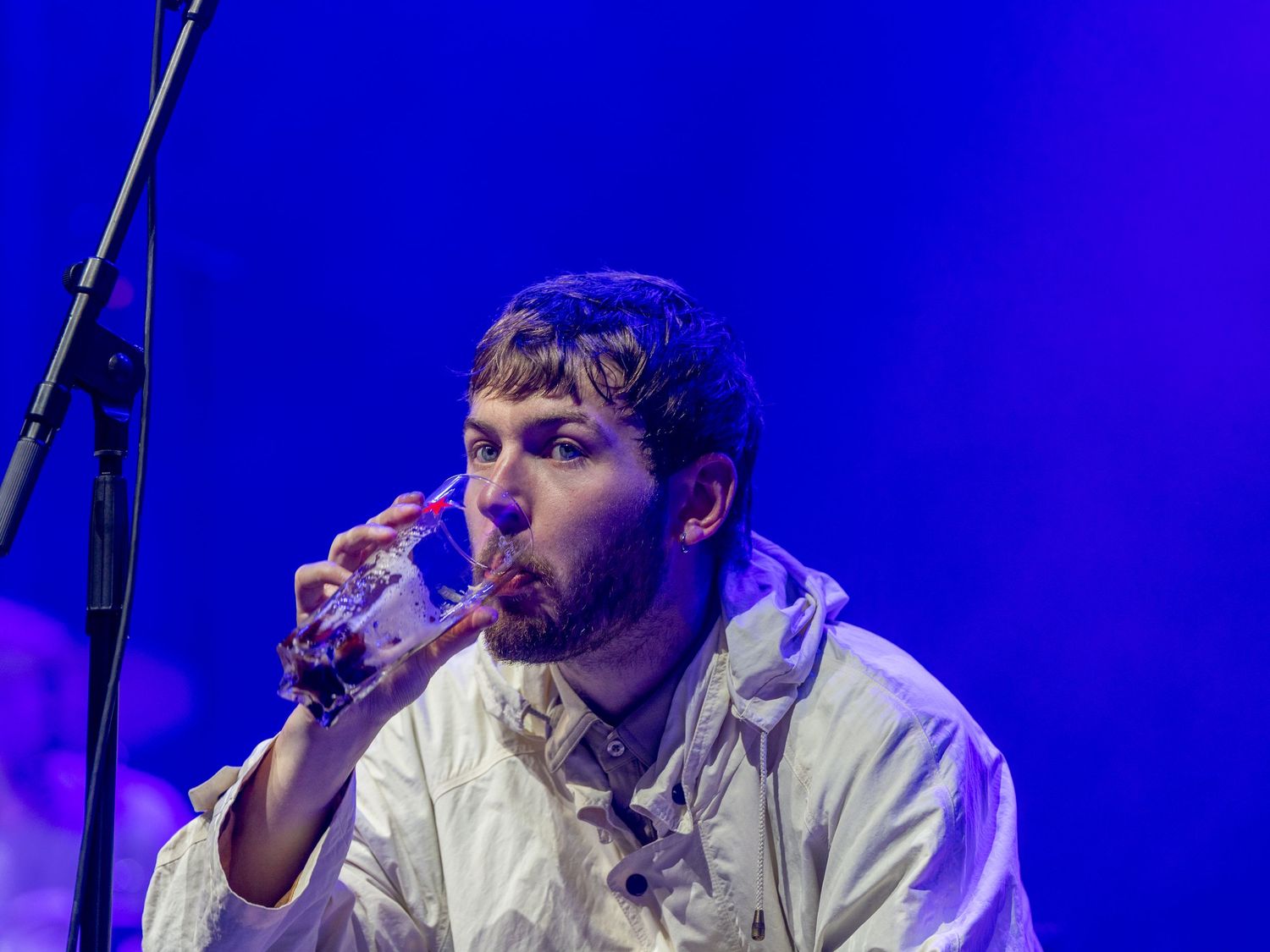 Singer performing on stage illuminated by intense blue lighting during concert performance.