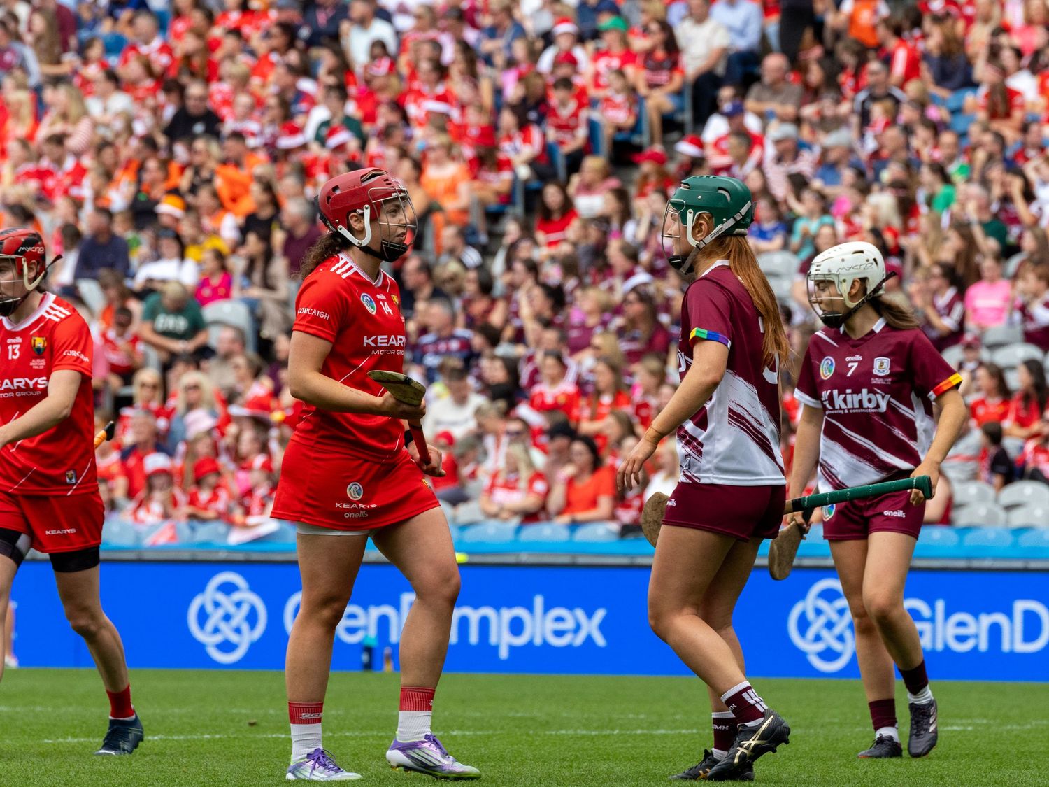 Rugby players in red and maroon jerseys competing in a crowded stadium during an intense match.