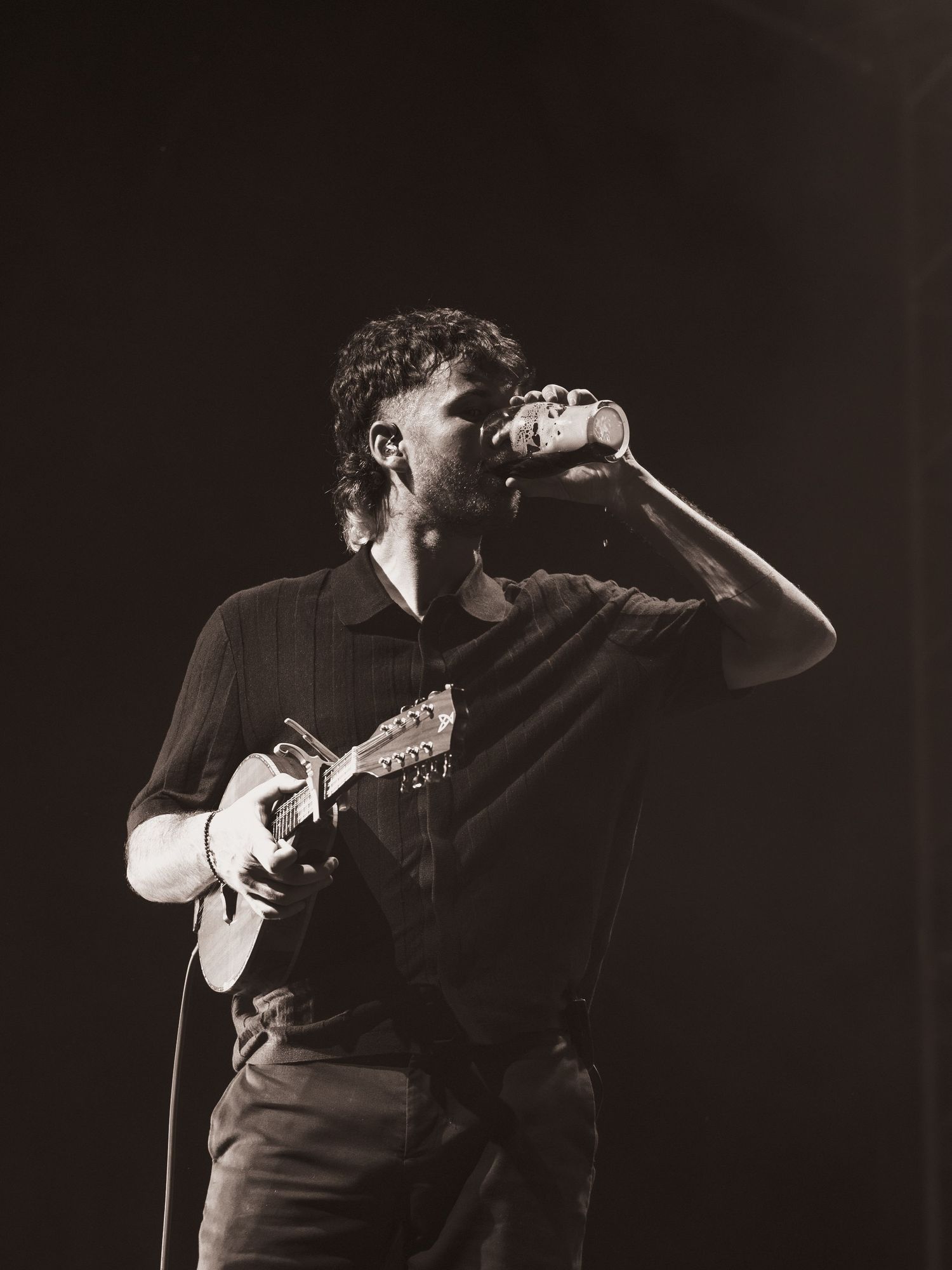 Dramatic black and white shot of performer singing on stage with intense expression.