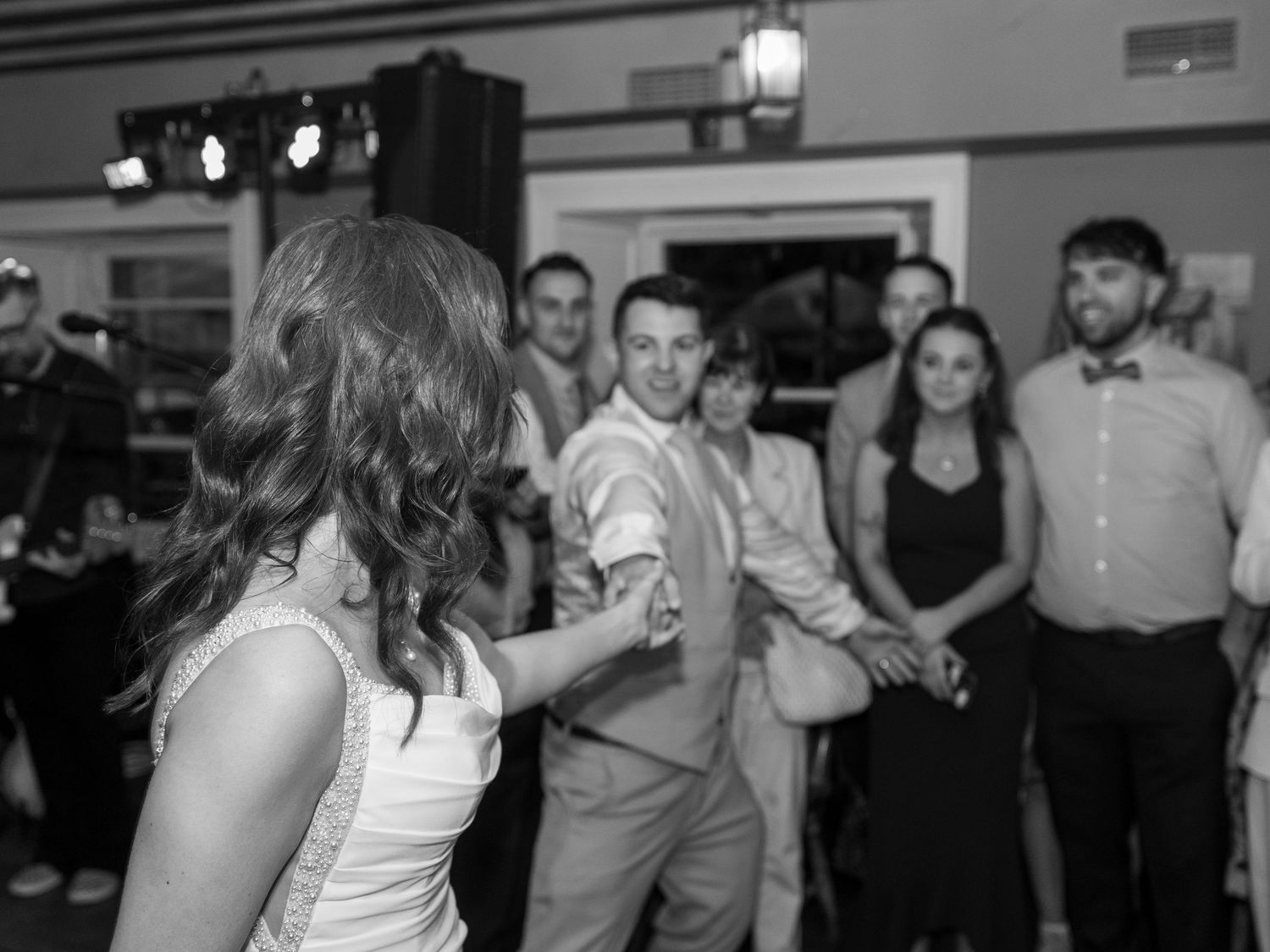 Wedding party dancing and having fun on indoor dance floor.