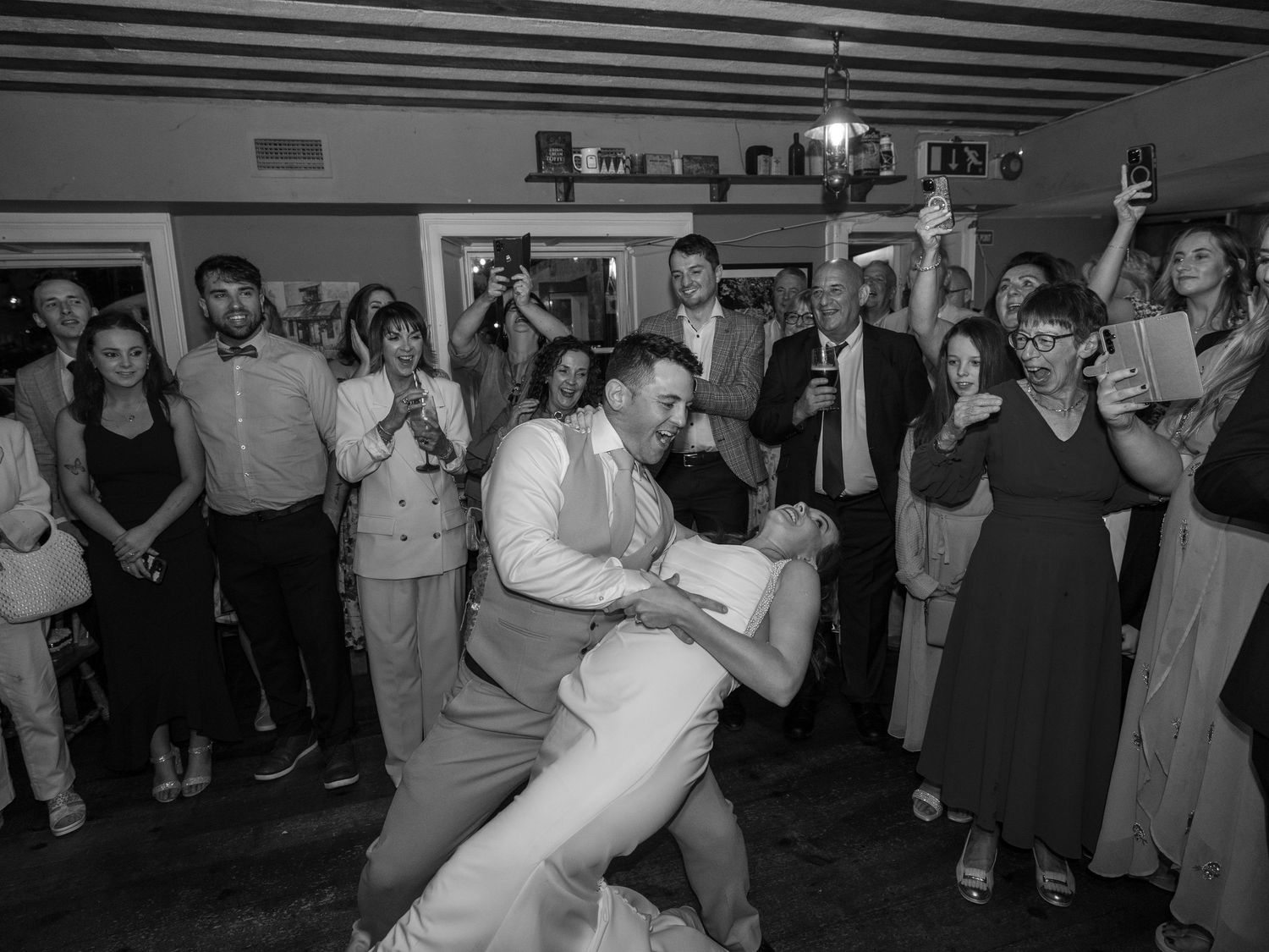 Wedding reception guests dancing and celebrating in black and white.