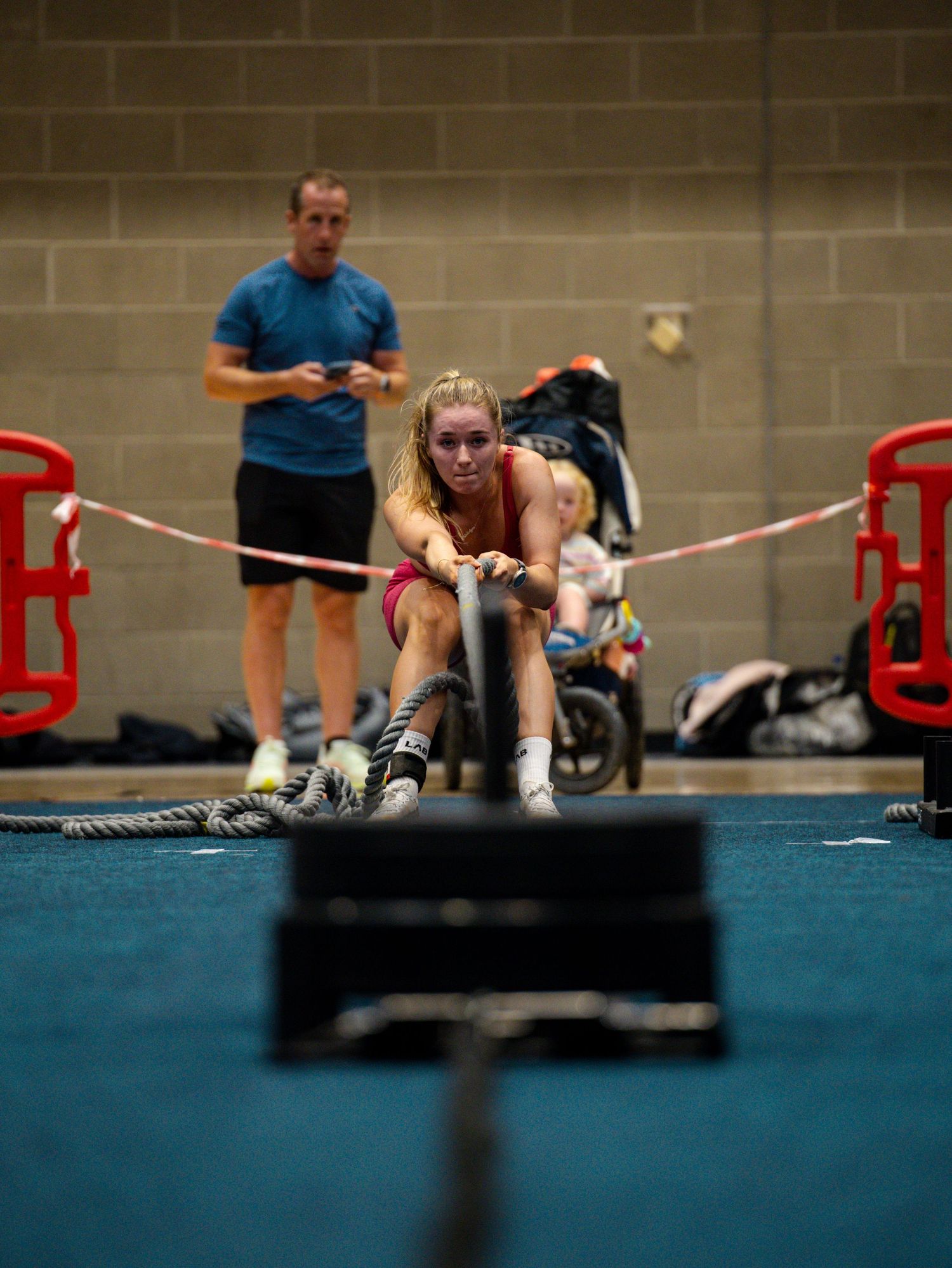 Athletes perform intense battle rope exercises during a high-energy CrossFit training session on blue gym mats.
