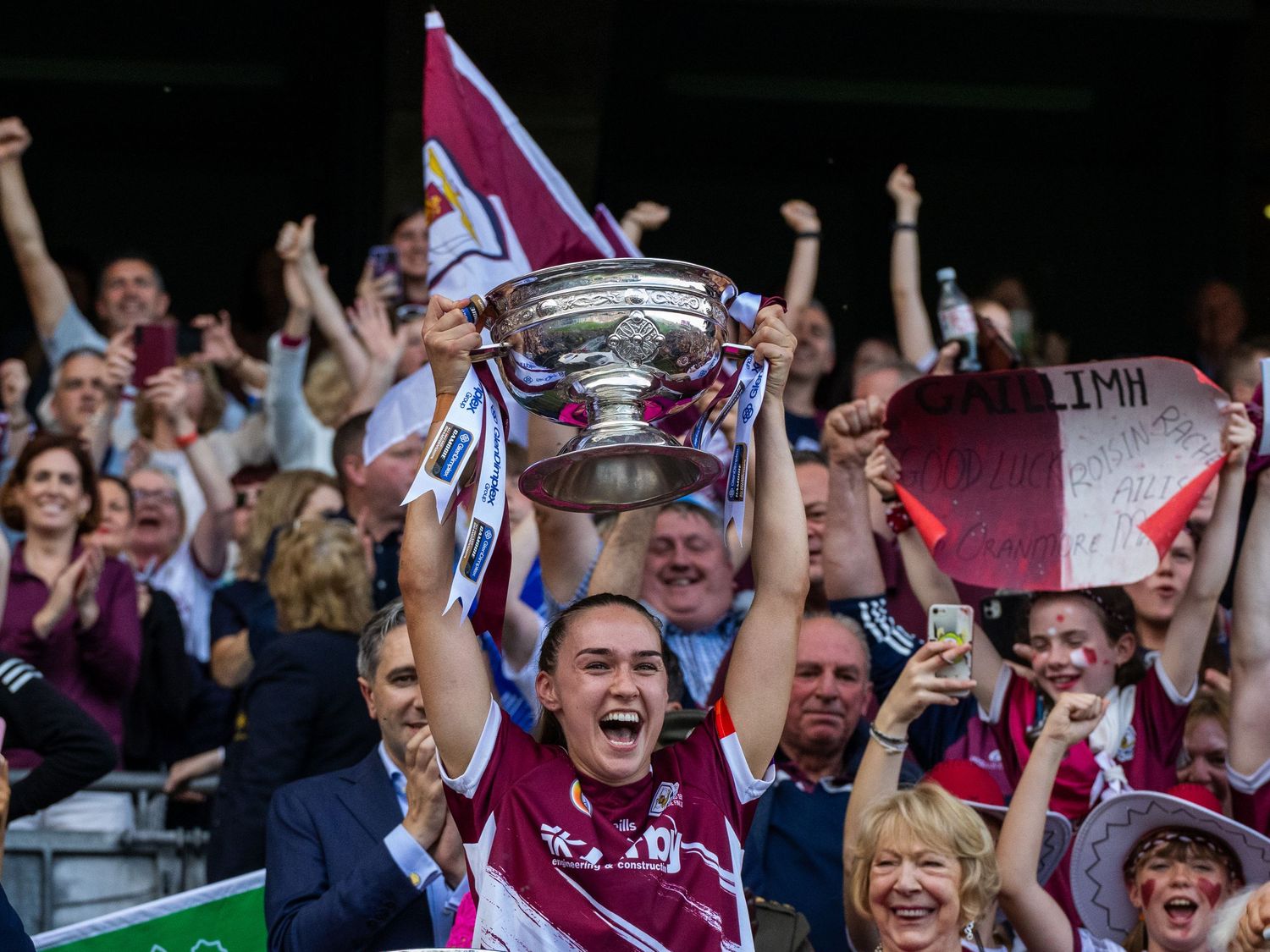 Sports fans celebrate with trophies and cheers during a championship victory celebration at a stadium.