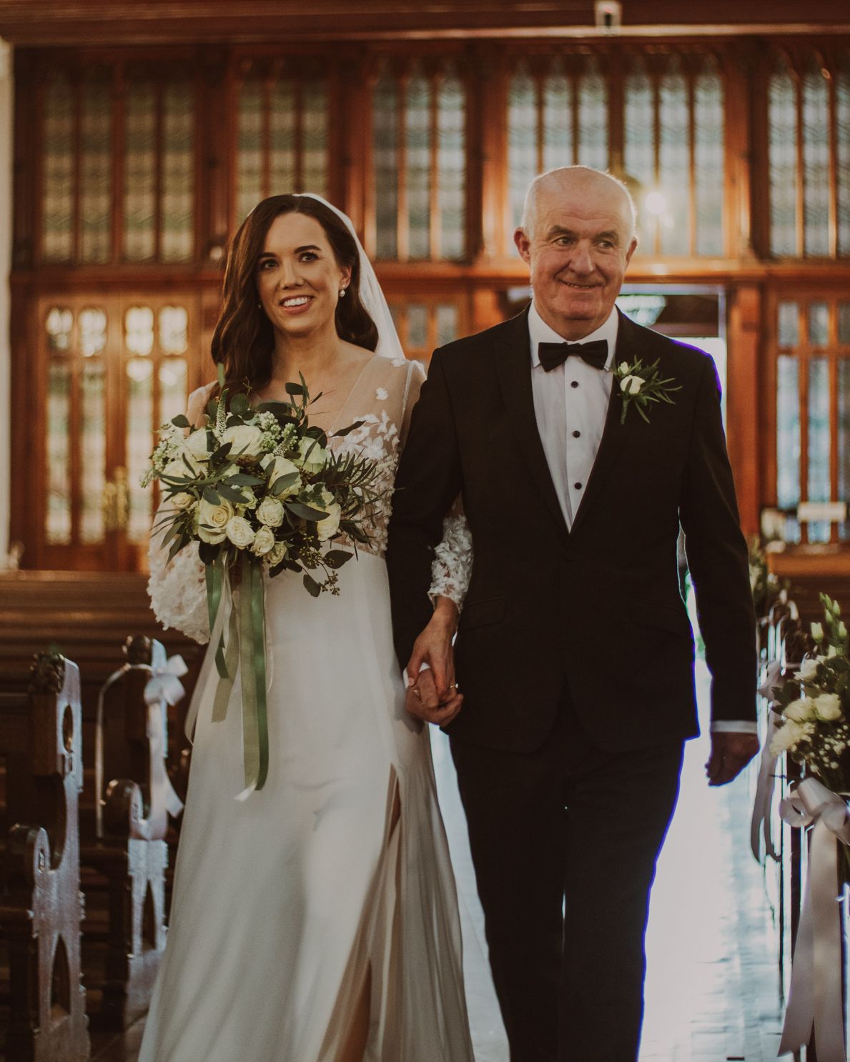 A bride is  being walked down the aisle by her father