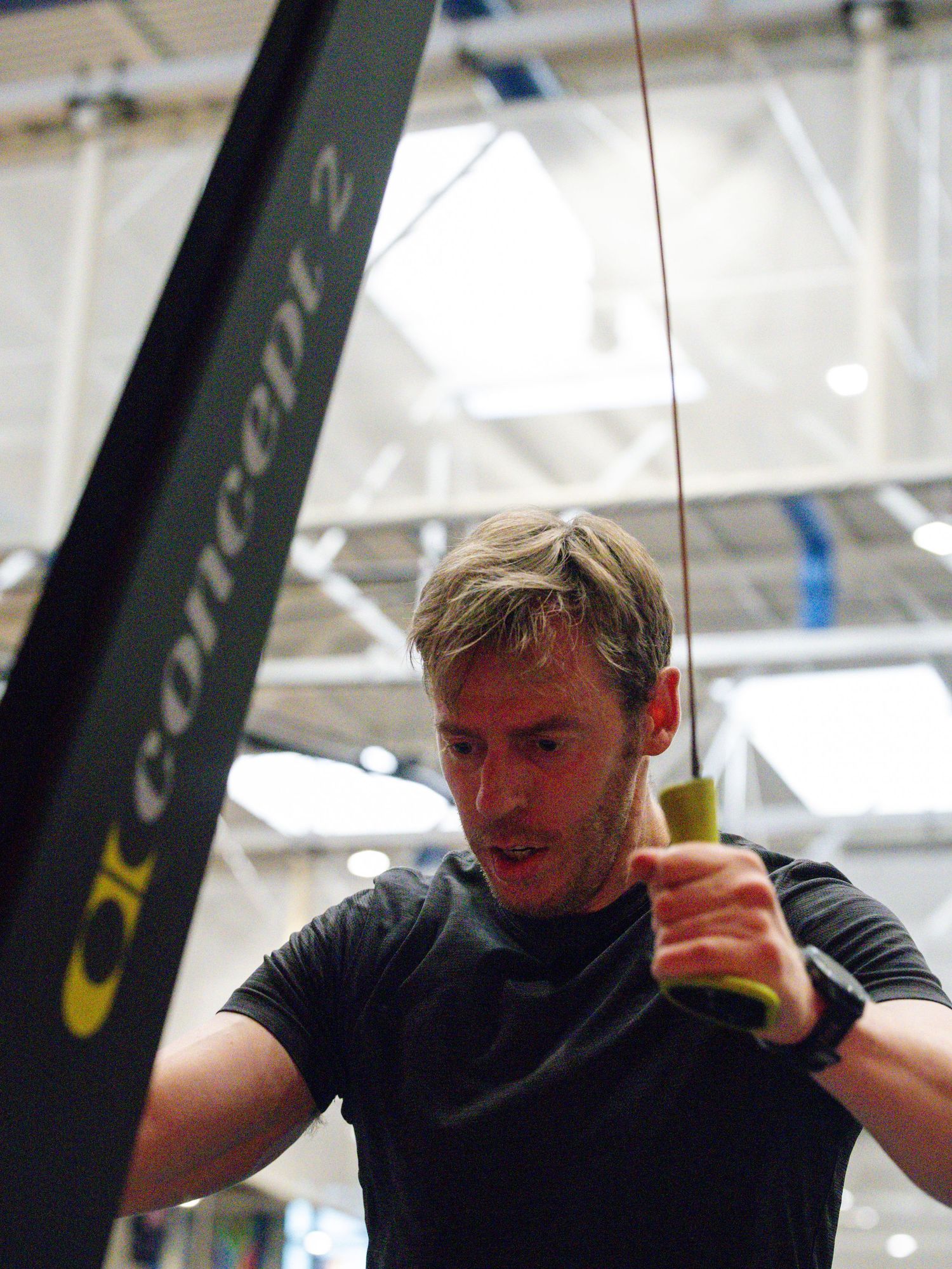 A person in a black t-shirt works out using exercise equipment in a fitness facility.