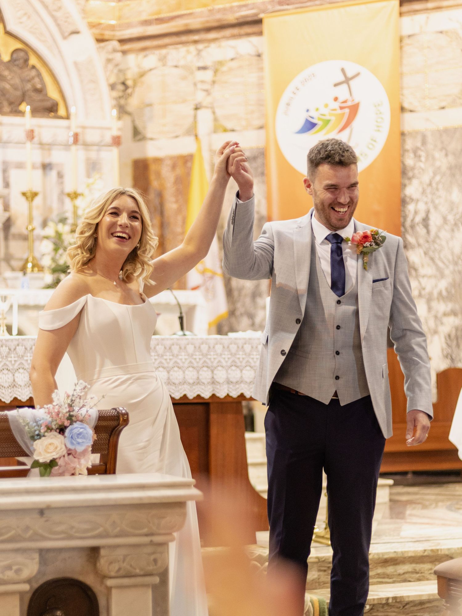 Happy newlyweds celebrating after exchanging rings in historic church setting.