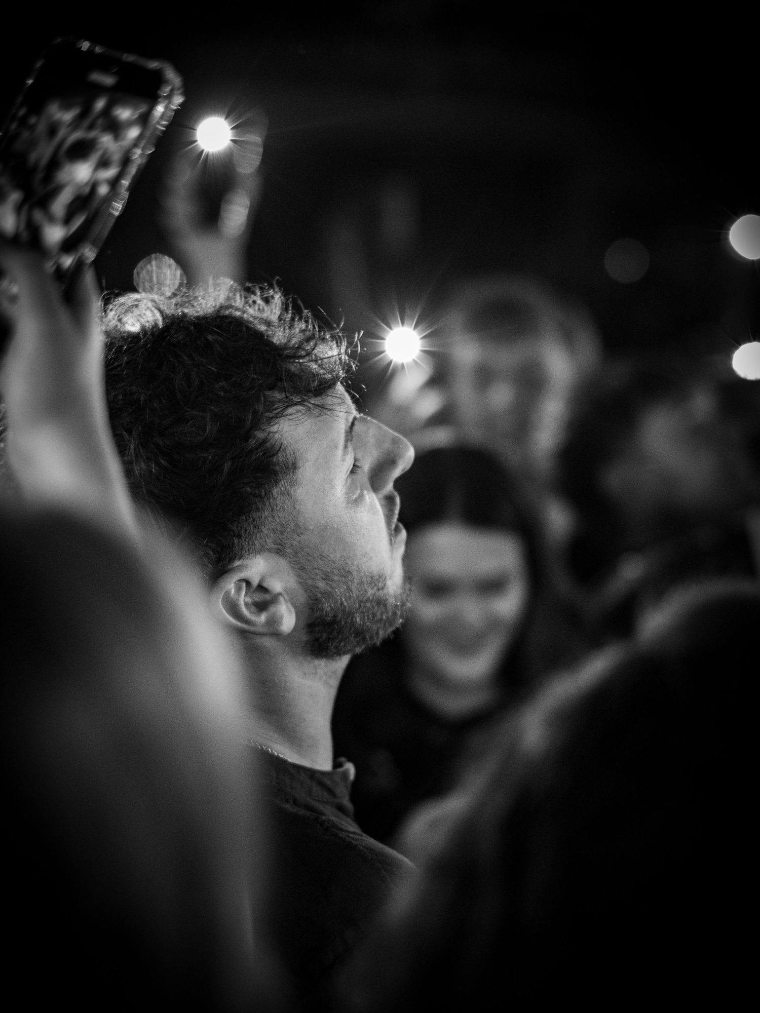 A series of black and white profile shots showing a person in a dark, dimly lit environment with bokeh lights in background.