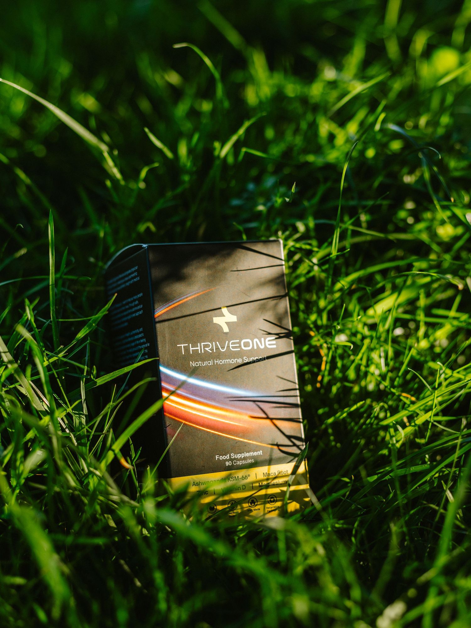Black product boxes arranged in grass with shallow depth of field photography.