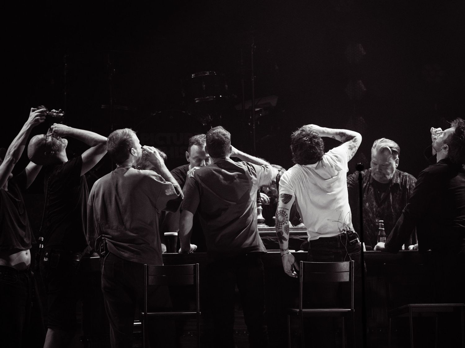A series of black and white photographs showing people seated in a row with their hands behind their heads.