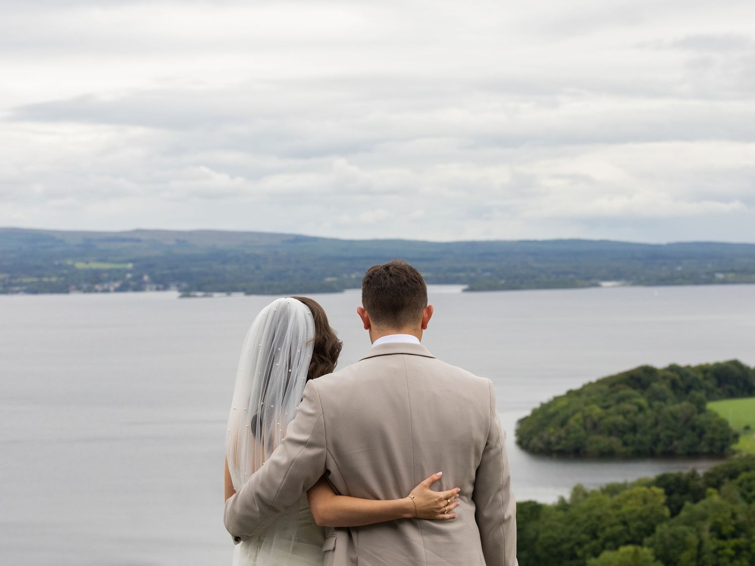 Scenic waterfront view overlooking lakes and hills on cloudy day.