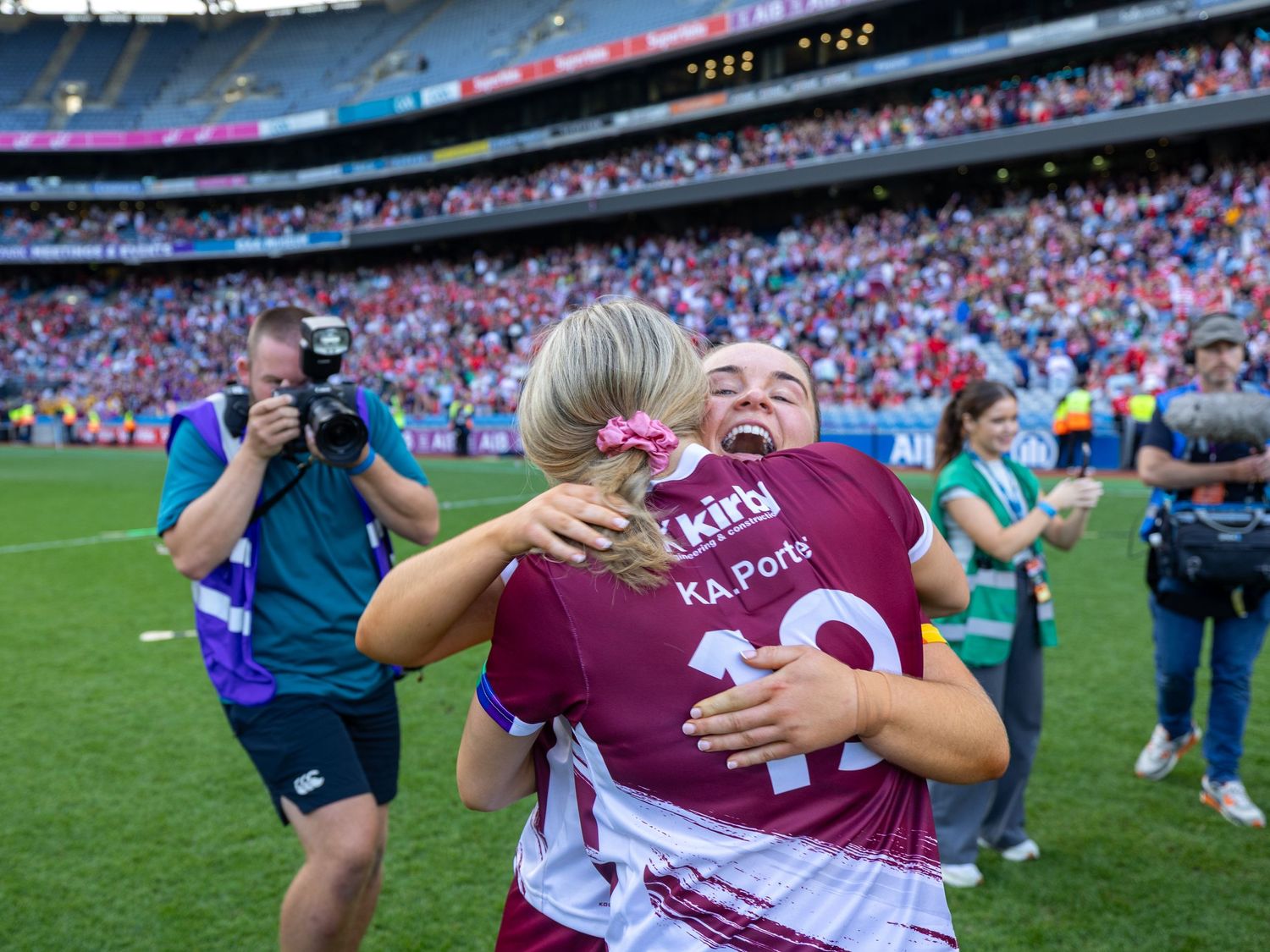 Players celebrate on the field after a victory at a large stadium filled with spectators.
