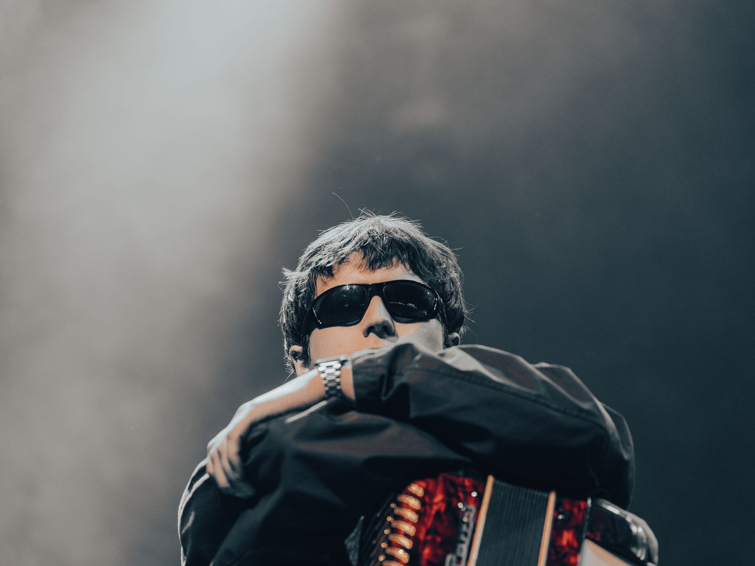Performer in dark clothing against moody blue stage lighting during live show.