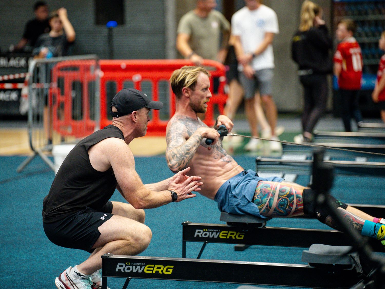 Athletes training on rowing machines in a CrossFit gym during a workout session.