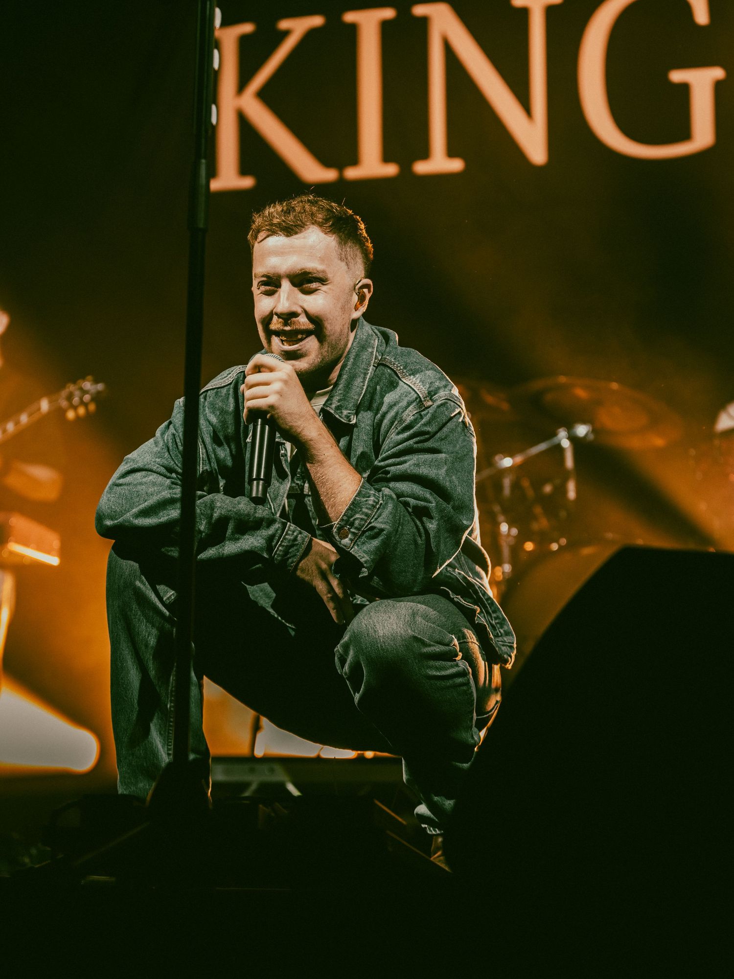 Dramatic concert performance with 'KING' text displayed prominently against dark stage lighting.