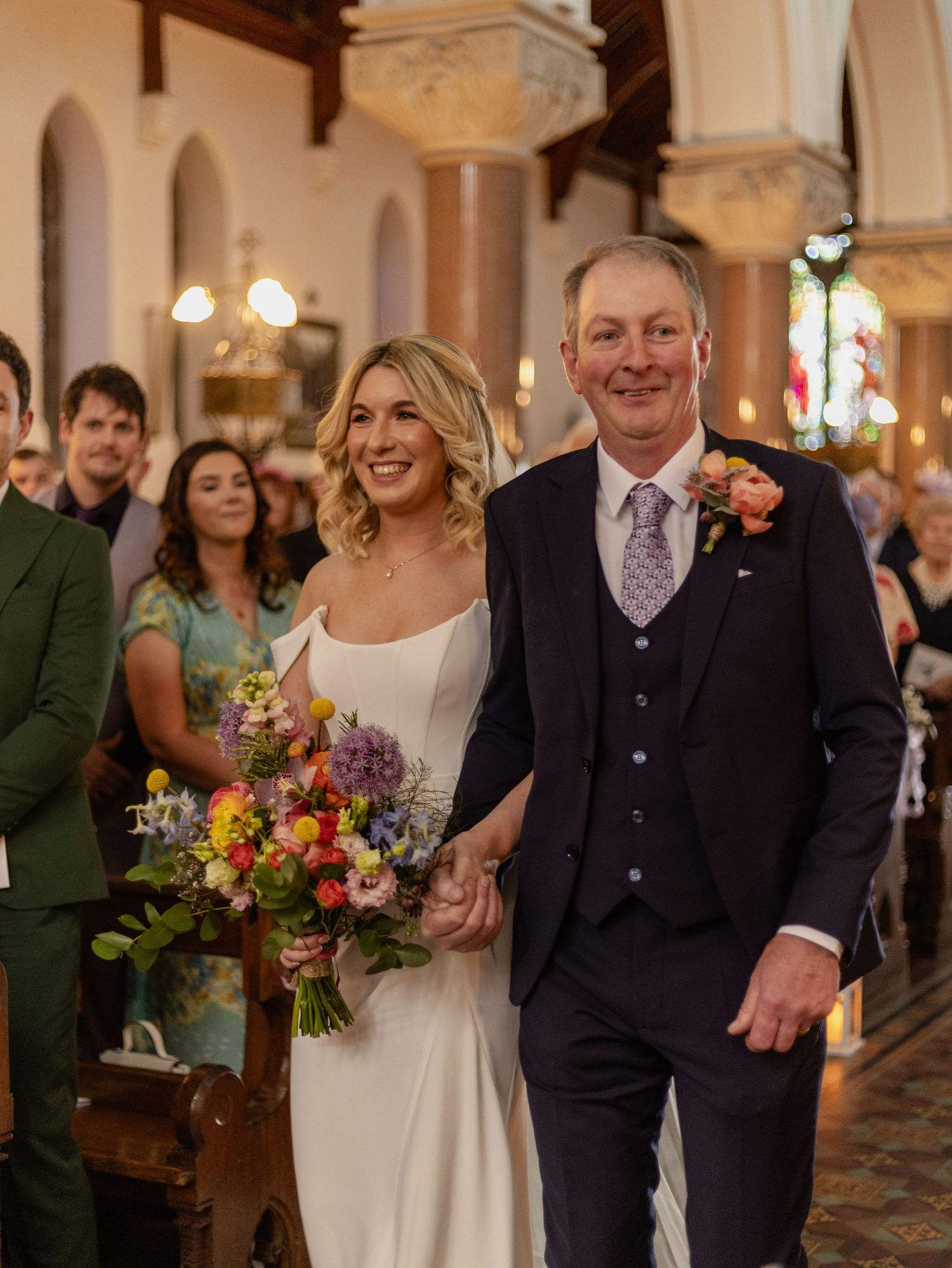 Wedding ceremony procession in ornate church interior with elegant architectural details.