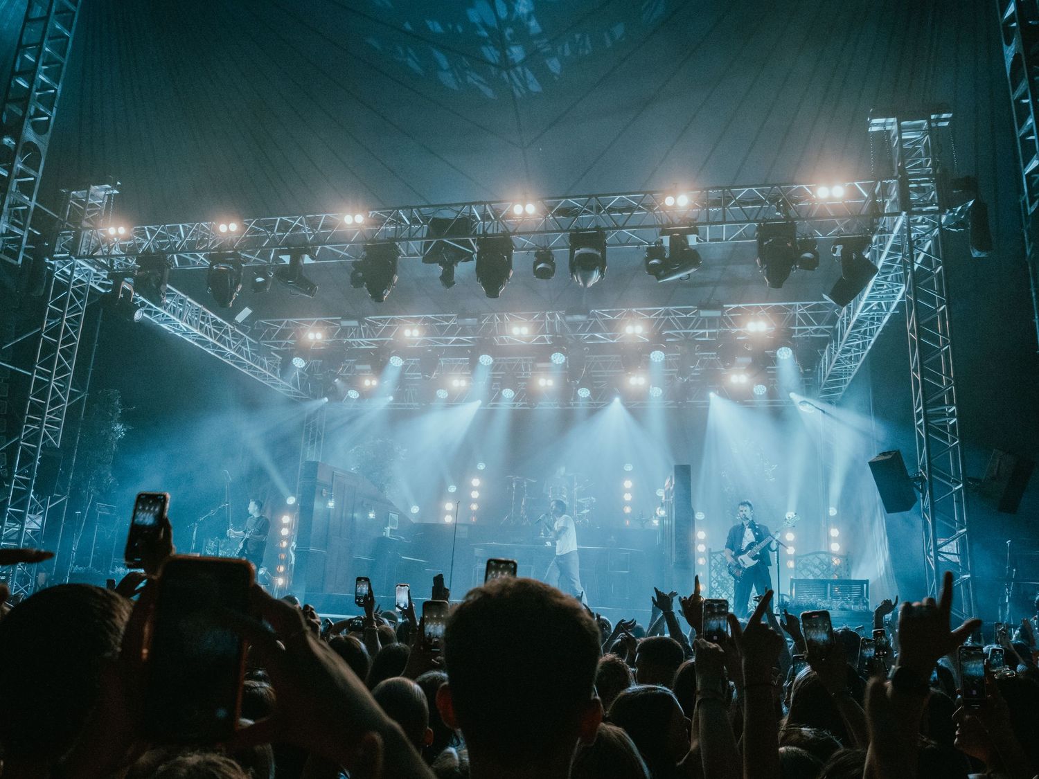 Concert stage with dramatic blue lighting and silhouetted crowd at a nighttime music festival.