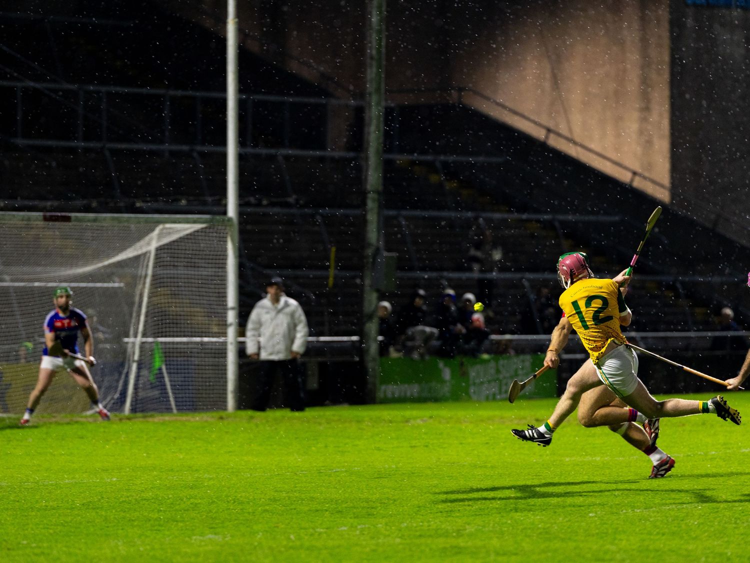 Soccer goalkeeper makes a diving save attempt to block the ball during an intense match on a grass field.
